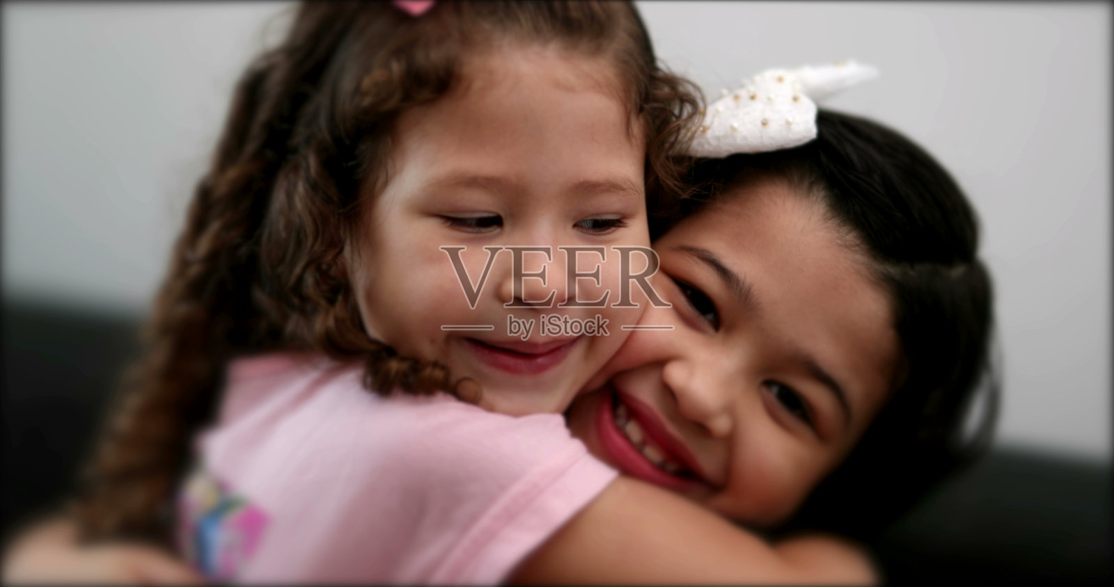 可爱的混血小姐妹互相亲吻。孩子们手足相爱照片摄影图片