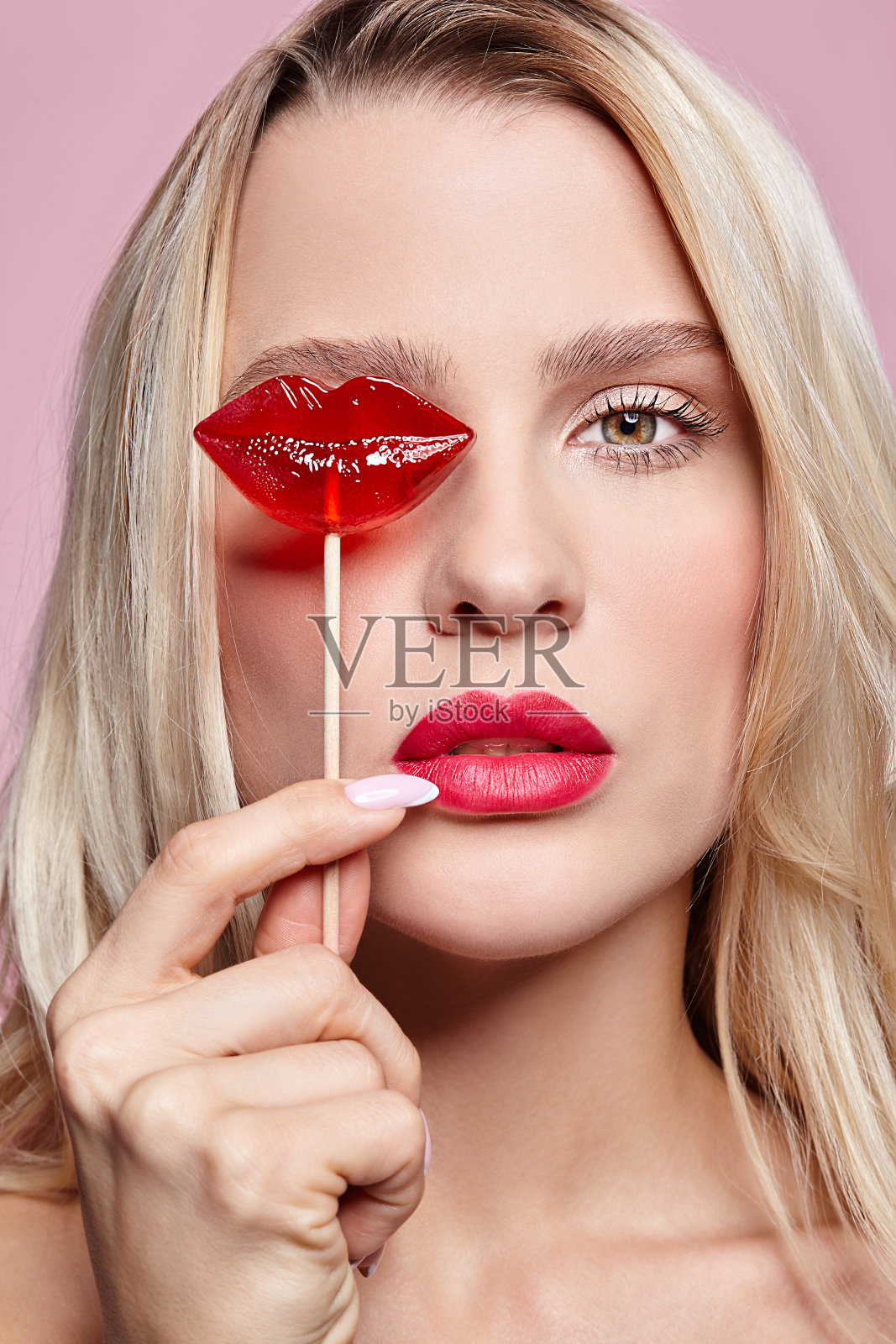 金发女人的肖像关闭糖果她的眼睛..红色的女性嘴唇形状像棒棒糖。甜食的概念照片摄影图片