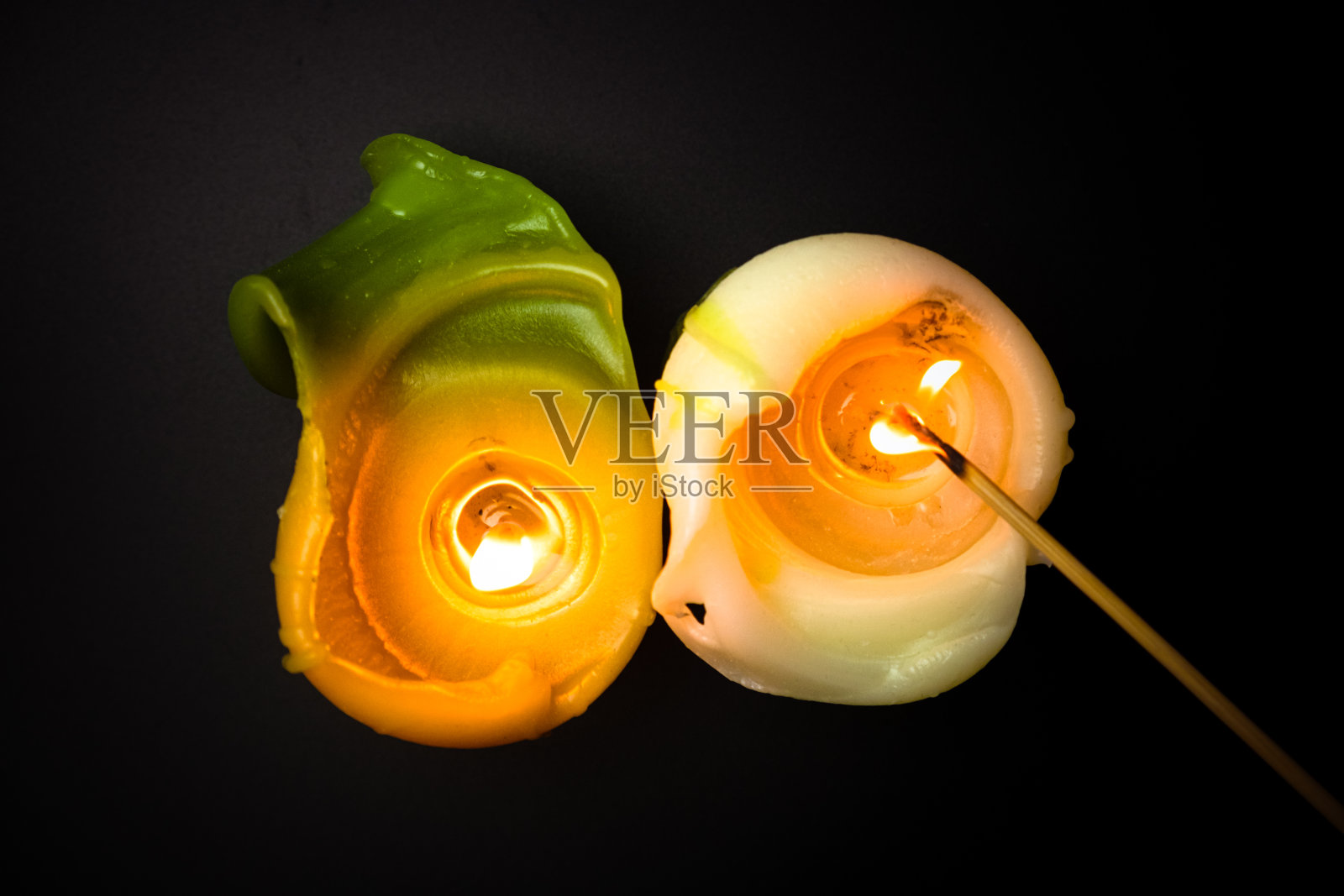 美丽的燃烧蜡烛在黑色背景俯视图。绿色和白色的香味蜡烛。自然的蜡烛。照片摄影图片