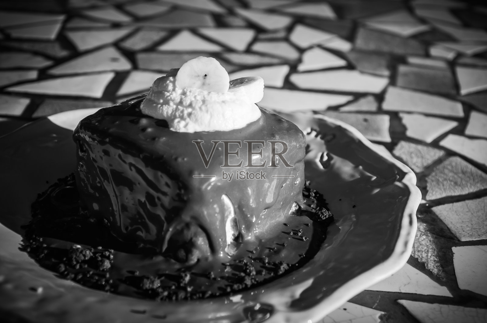 巧克力蛋糕上面淋上鲜奶油,在白色的盘子里放上香蕉照片摄影图片