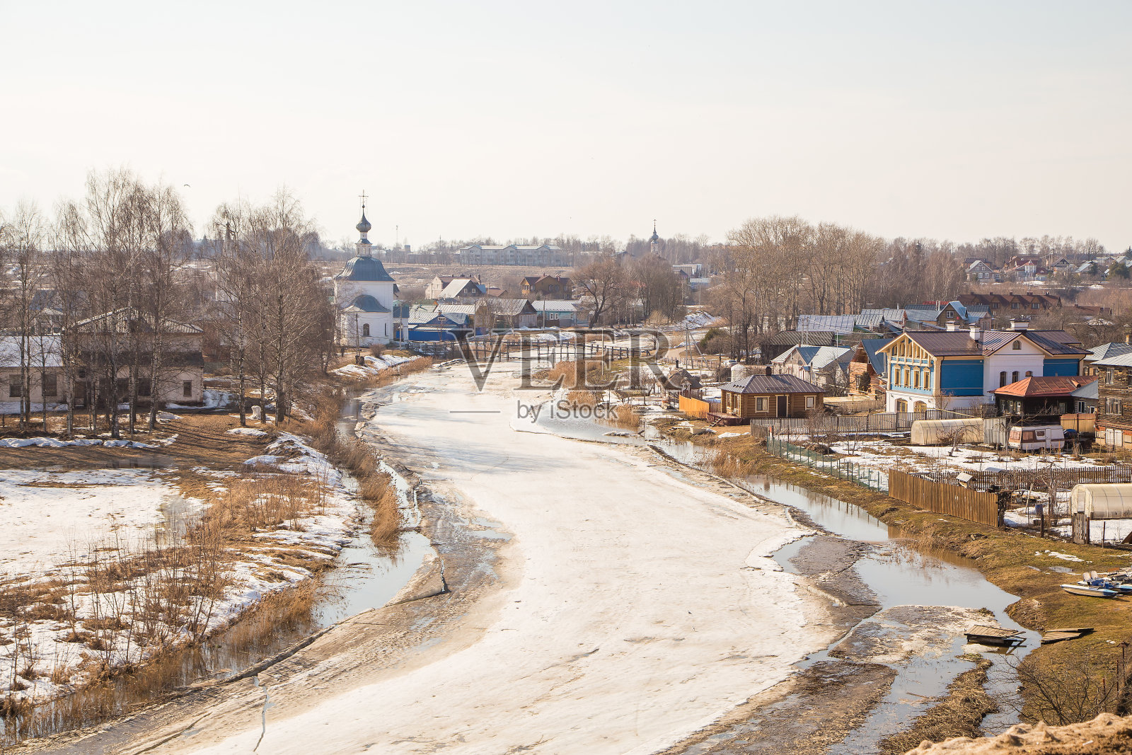 一条弯弯曲曲、结了冰的河流伸向远方,河岸上有木屋照片摄影图片