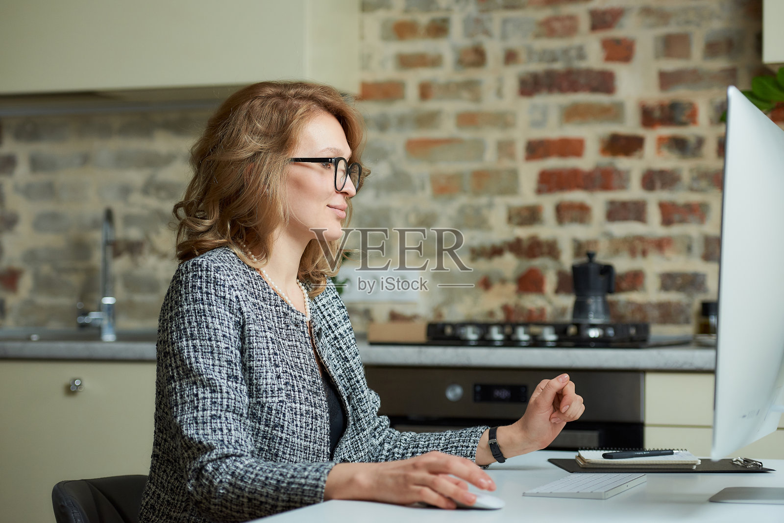 一位女士在台式电脑前与她的员工开视频会议。照片摄影图片