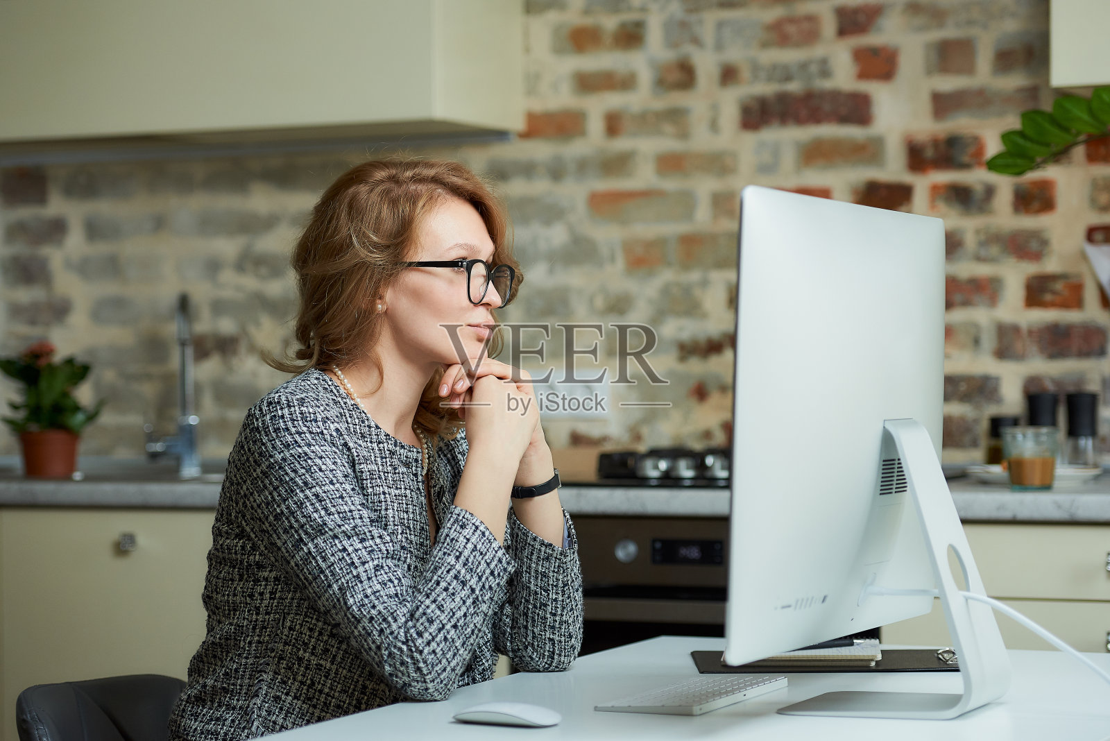一位女士在台式电脑前与她的员工开视频会议。照片摄影图片