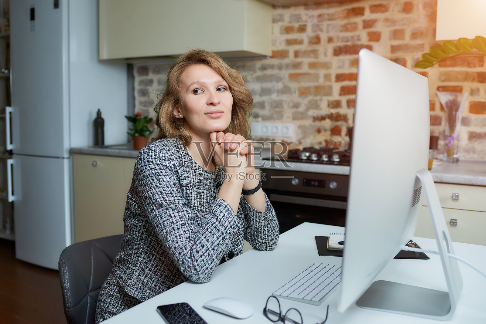 一位女士在台式电脑前与她的员工开视频会议。照片摄影图片