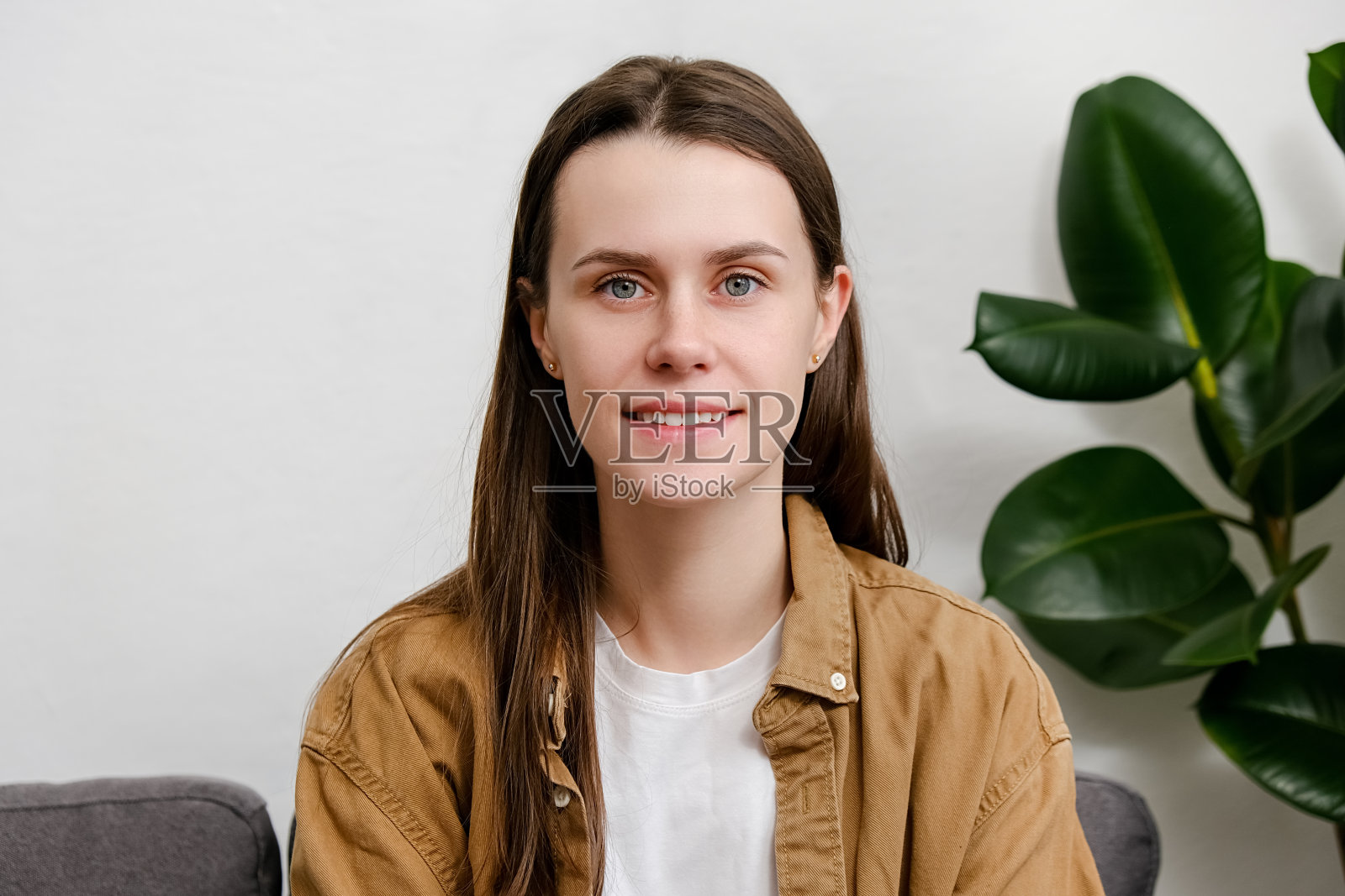 年轻迷人的快乐微笑的白人女孩学生或专业人士的特写肖像在现代家庭室内看着相机摆姿势。美丽可爱的黑发女人20岁享受周末照片摄影图片