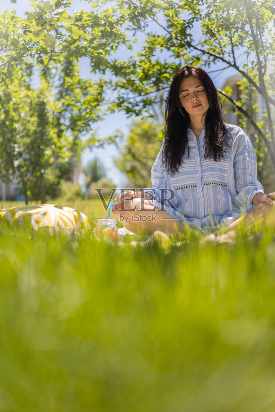 放松的女人坐在莲花的位置上格子享受早晨冥想在夏季花园公园照片摄影图片
