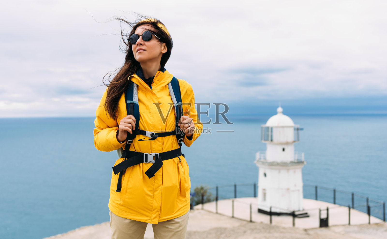 一个旅行者背着旅行包站在大海的背景下。旅游、旅游和积极的生活方式理念。一个女性旅行者的肖像在蓝色的大海的背景上。本空间照片摄影图片