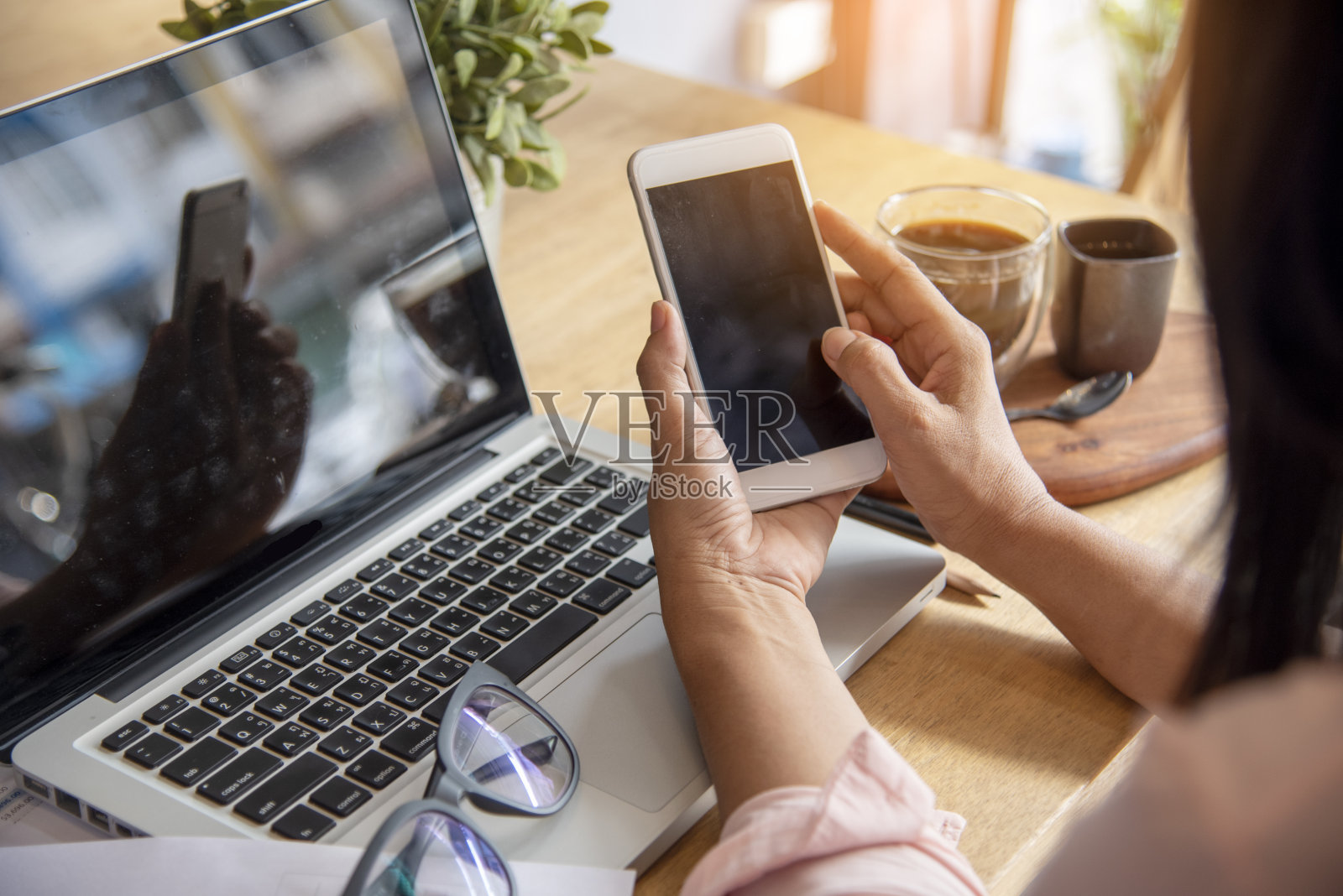 商务女性在办公桌上使用智能手机和笔记本电脑。计划分析市场数据。年轻女性的手在办公室工作,公司的业务信息。照片摄影图片