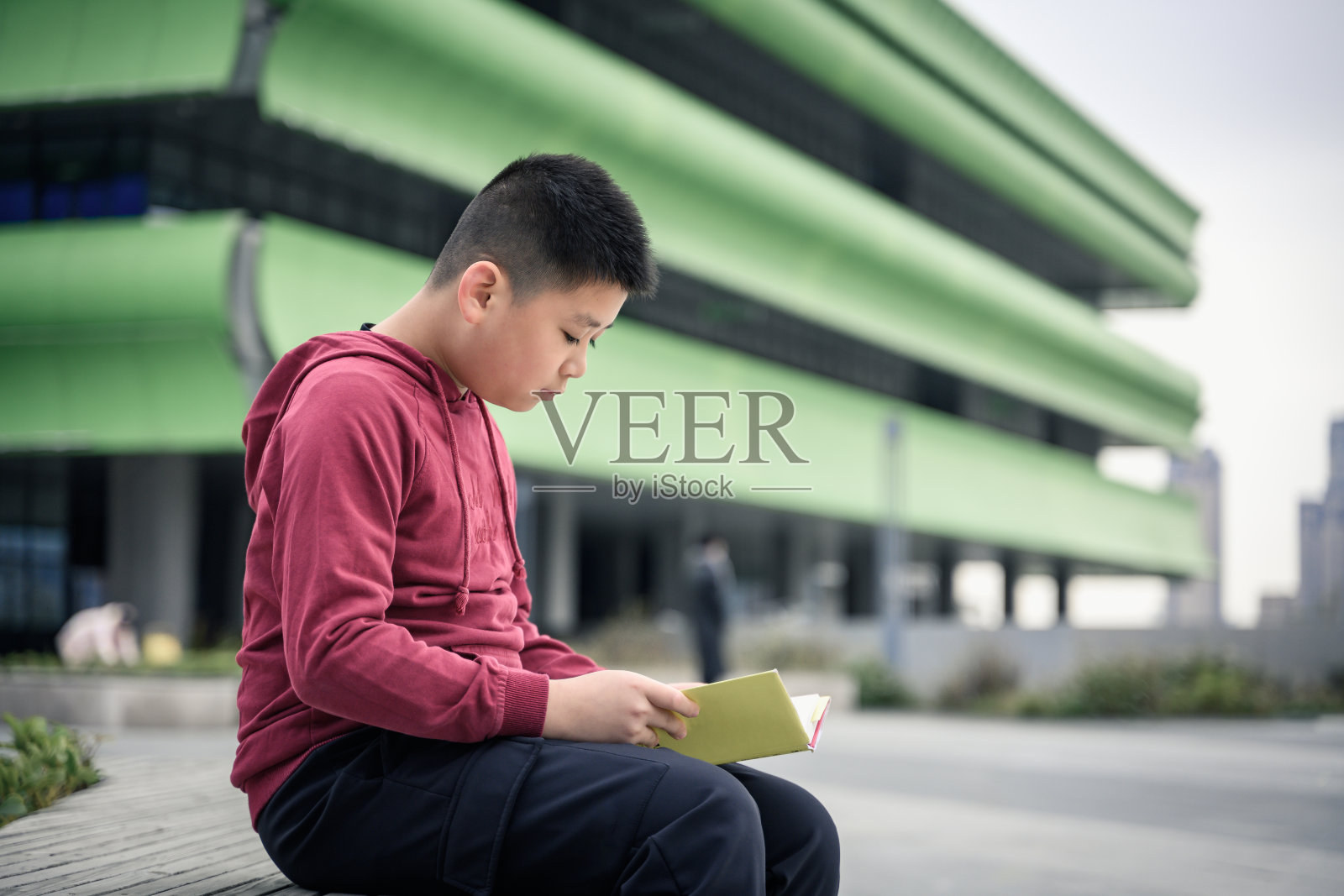 一个亚洲男孩坐在花园里看书照片摄影图片