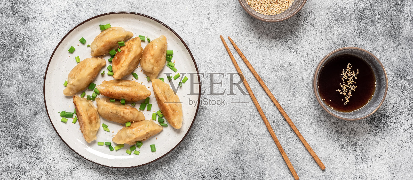 传统的亚洲饺子,葱花和酱油。灰色混凝土grunge背景。俯视图,平躺,横幅。照片摄影图片