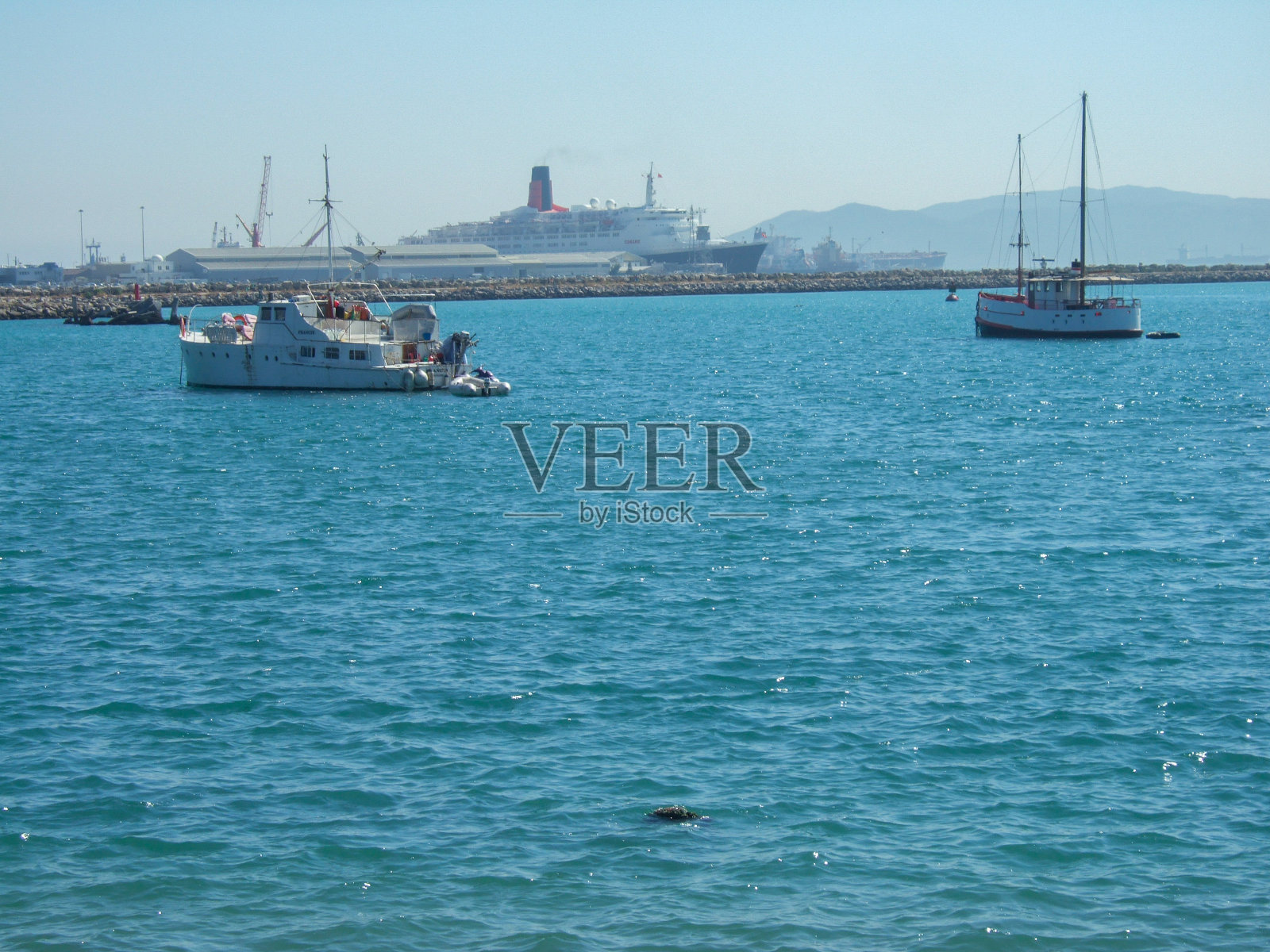 在西班牙阿尔赫西拉斯的集装箱港口前,一些渔船和帆船。在背景中你可以看到一艘蒸汽渡船照片摄影图片