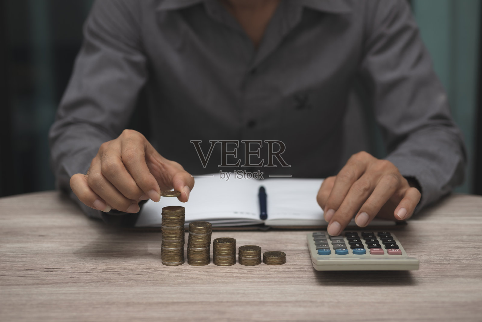 节约资金和会计观念。商人为了投资和储蓄,把硬币塞到罐子里,用计算器计算财务管理。照片摄影图片