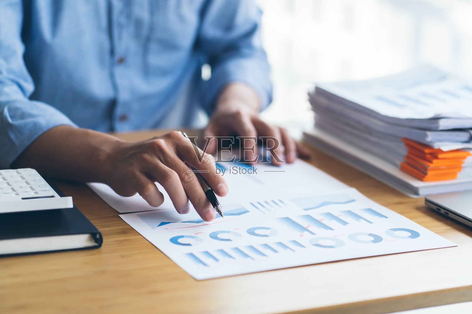 一个金融商人,一个年轻人用电脑和计算器分析金融数据,将数据计算并汇总成图表,向总统提出建议。照片摄影图片
