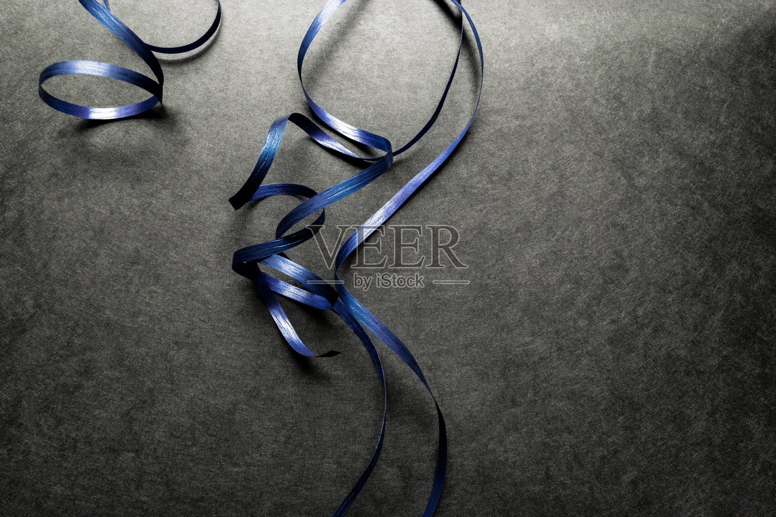 蓝色的包装丝带放置在黑色的表面背景照片摄影图片