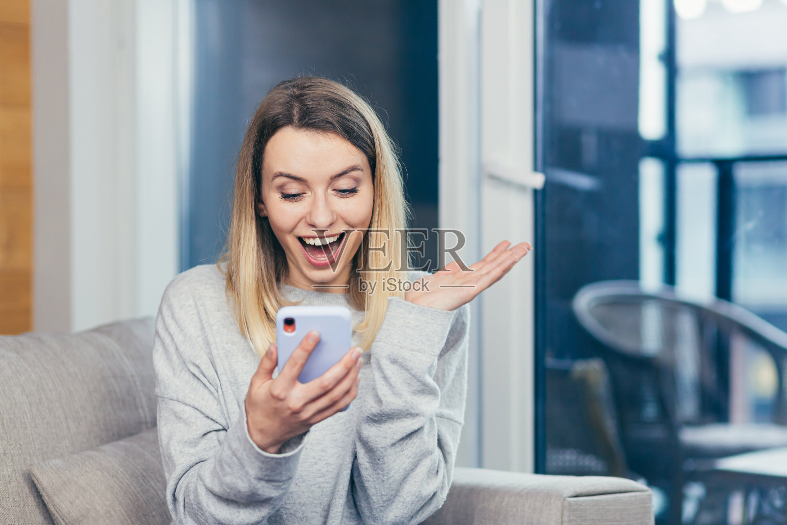 一名快乐美丽的年轻女子的肖像,她看着手机,很高兴获得了奖,得知了好消息照片摄影图片