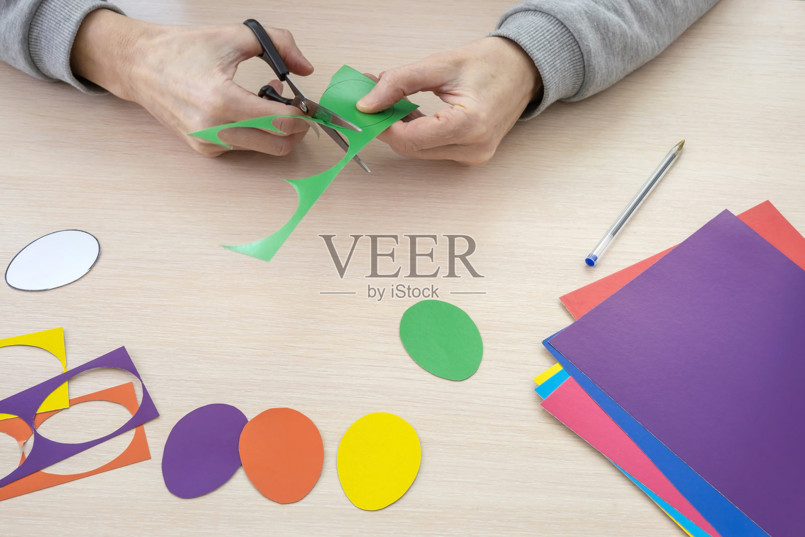 一名成年妇女用彩纸剪出复活节彩蛋照片摄影图片