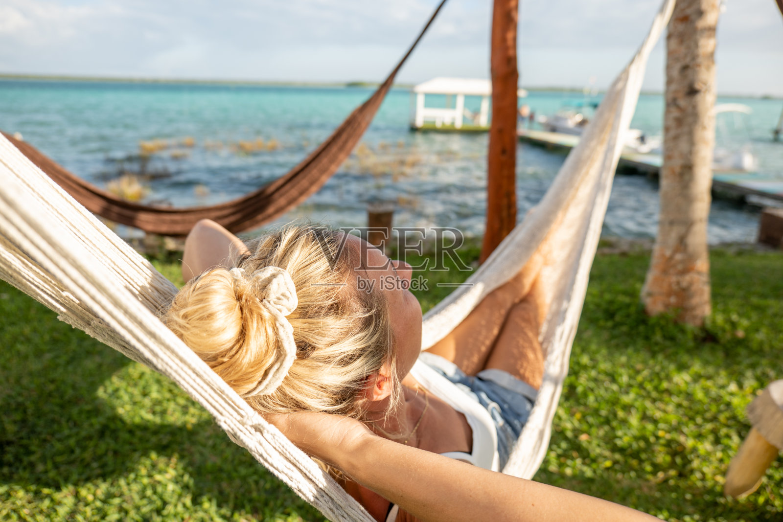 日落时,女人在吊床上放松,看湖景照片摄影图片