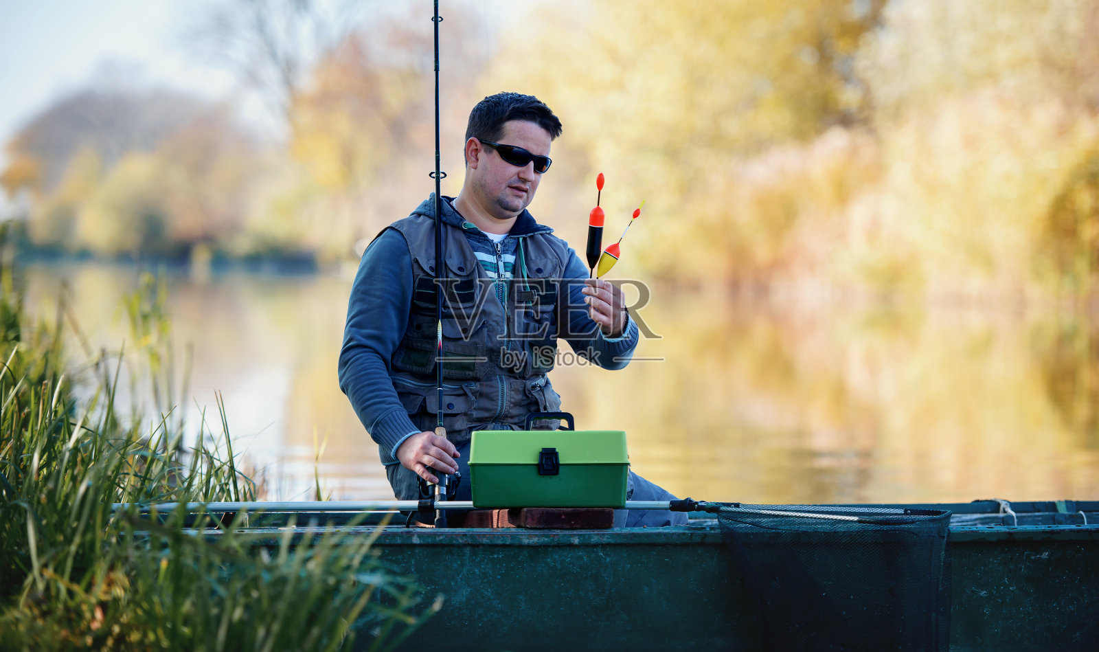 垂钓者一边选择钓具,一边试图在河上捕获一条战利品鱼。体育及康乐概念照片摄影图片