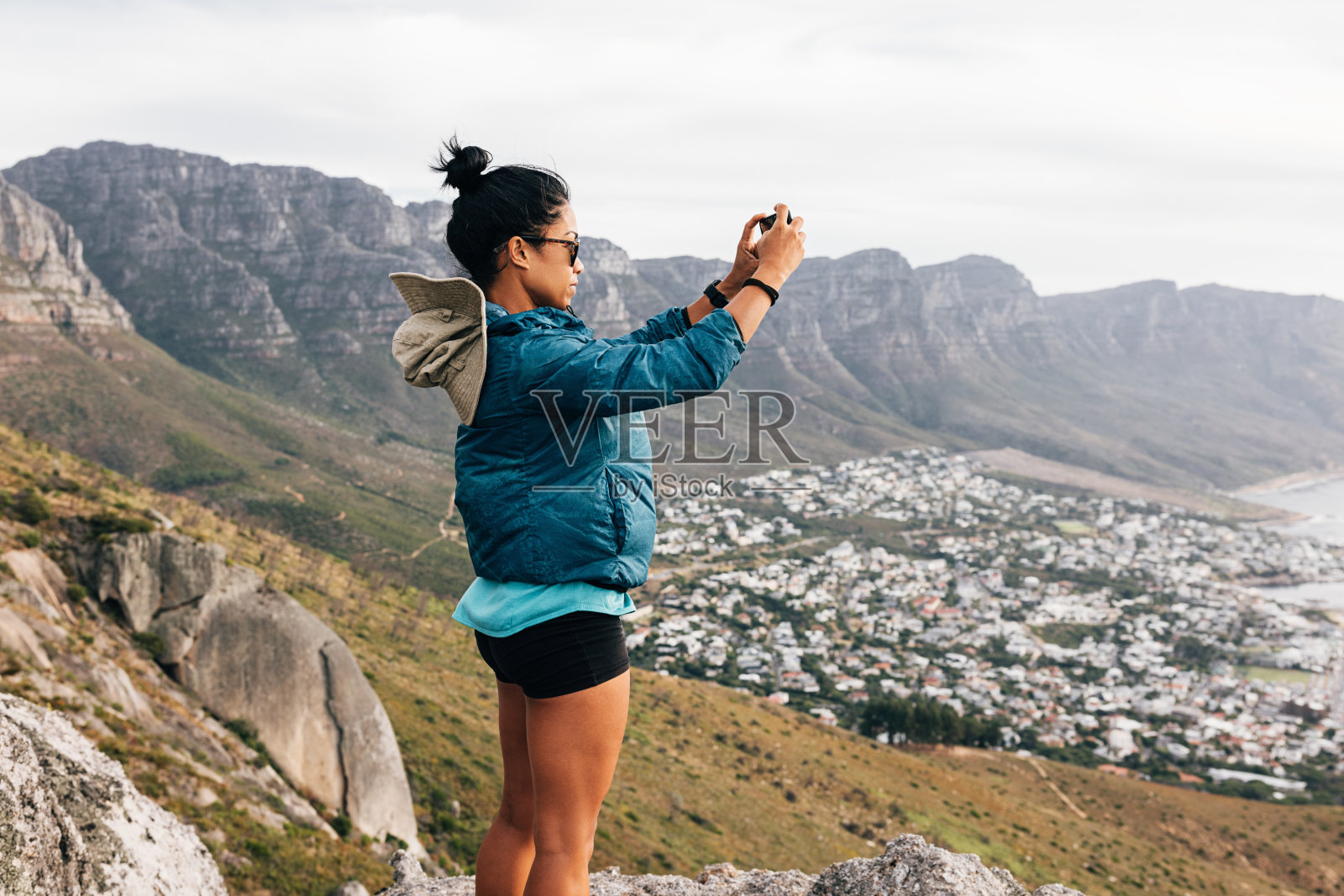 一名穿着运动服的妇女在徒步旅行时用手机拍照的侧视图照片摄影图片