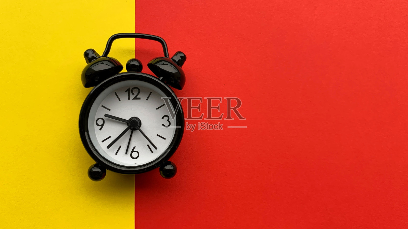 黄色和红色背景的闹钟开启。概念上的照片摄影图片