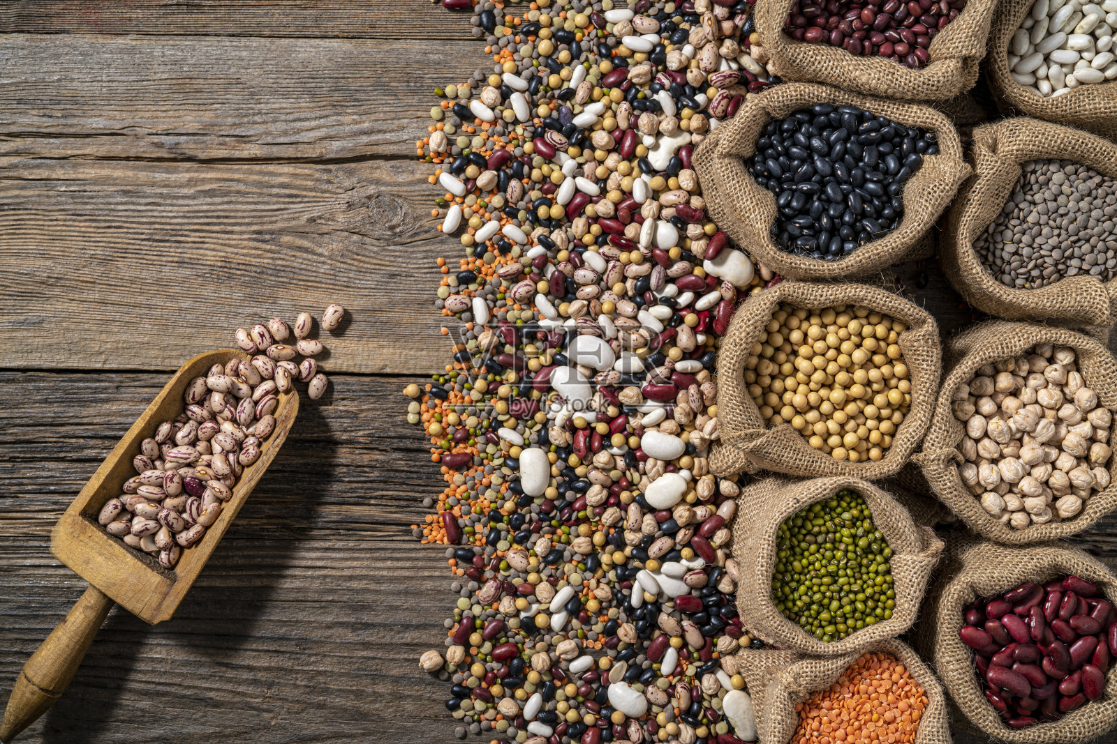 在一排用粗麻袋装着的什锦豆类,用木勺舀出一份质朴的木制品照片摄影图片