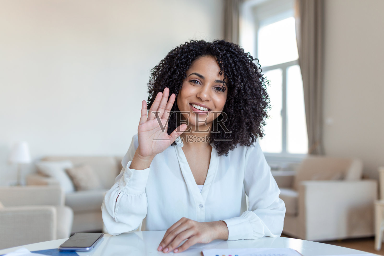 一名女商人坐在她的办公桌前进行视频通话。剪裁镜头的一个有吸引力的年轻女人用她的笔记本电脑在家里做视频电话照片摄影图片