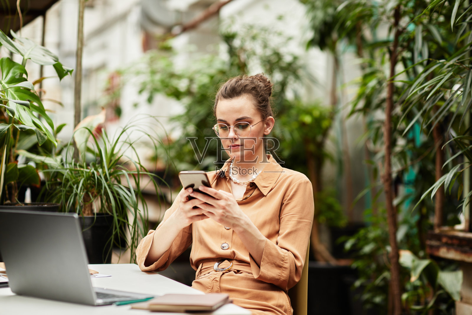 年轻的现代女商人用智能手机发短信或浏览数据照片摄影图片