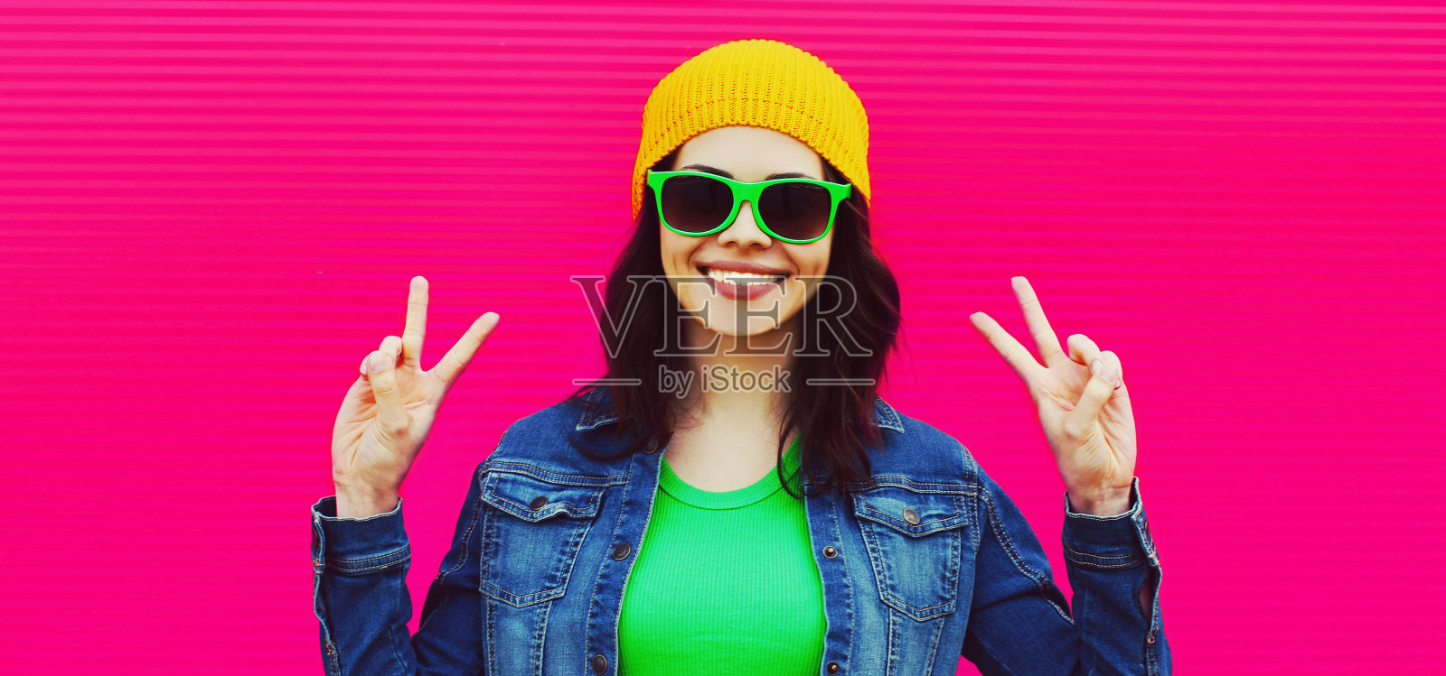 夏天的肖像快乐微笑的年轻女子穿着五颜六色的衣服,帽子在粉红色的背景照片摄影图片