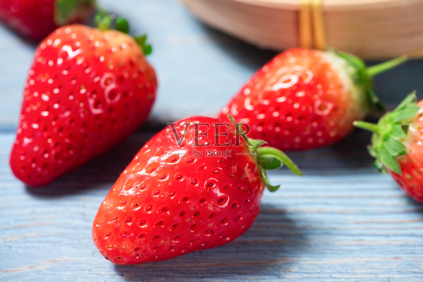 新鲜多汁的草莓放在蓝色的木桌上。照片摄影图片