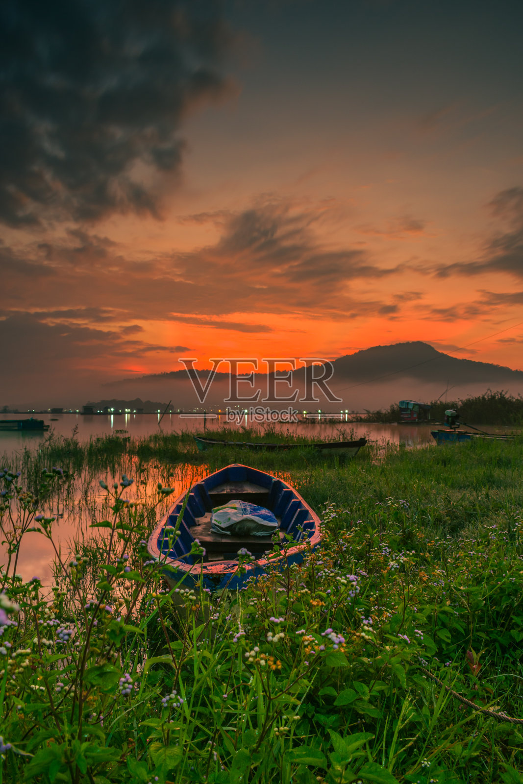 日出时分,在印度尼西亚西爪哇省库宁安市,在长满青草的湖边上泛舟照片摄影图片