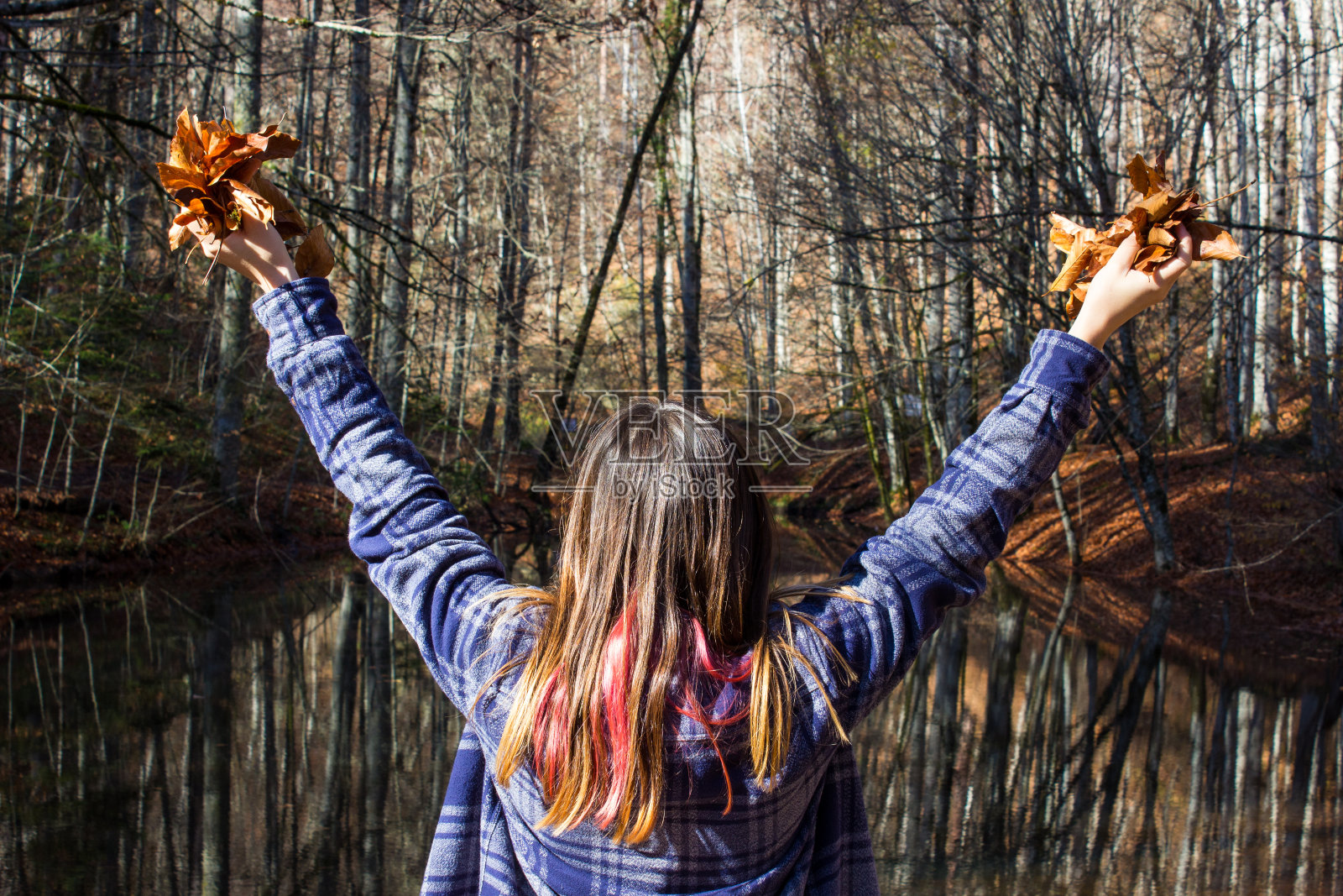 秋日的树林里,女人把秋叶抱在怀里。照片摄影图片