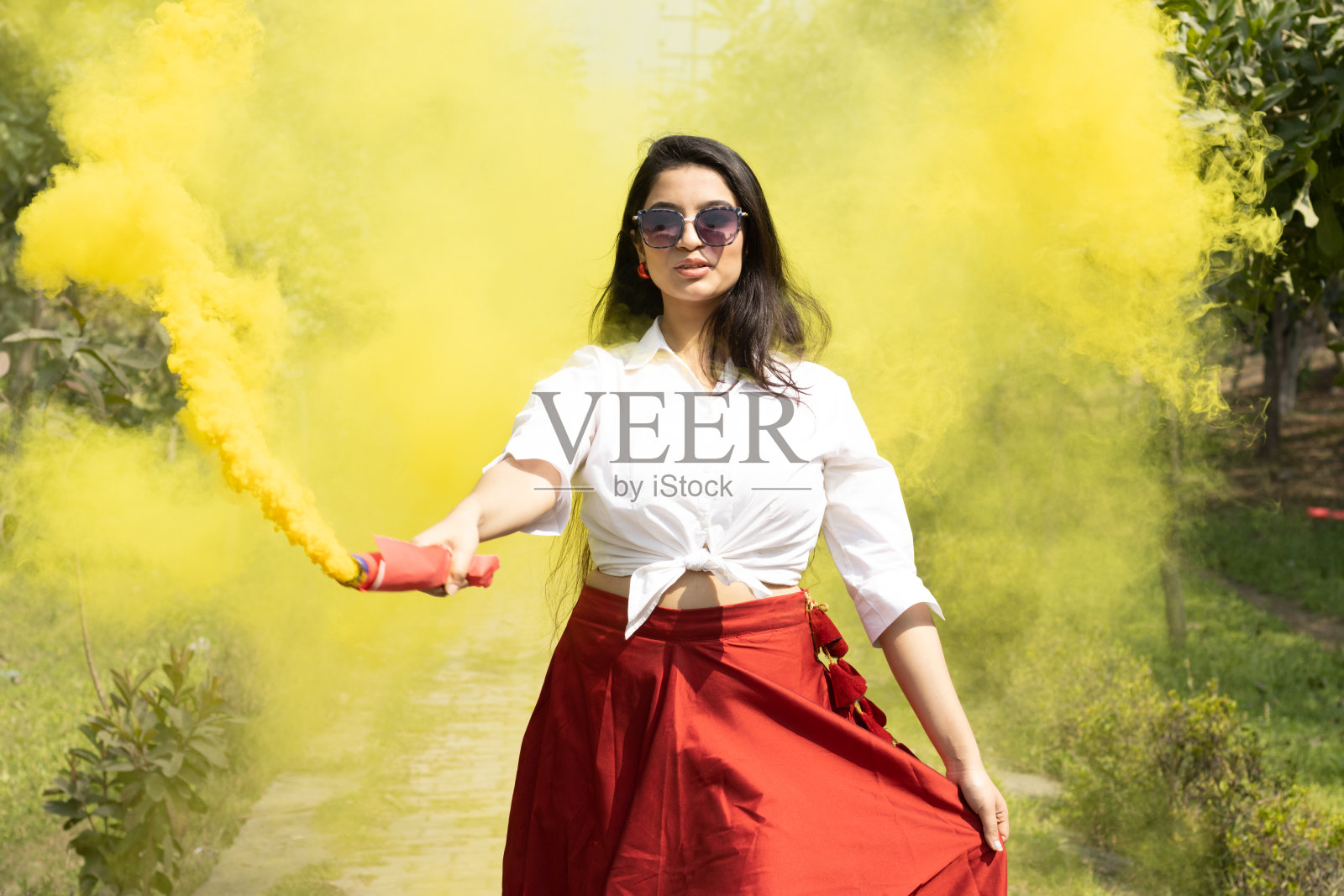 美丽的年轻女孩女人在春天的假期在公园庆祝胡里节的颜色黄色云团烟雾弹颜色干的颜色胡里节粉末颜色gulal啤酒节日的颜色胡里节照片摄影图片