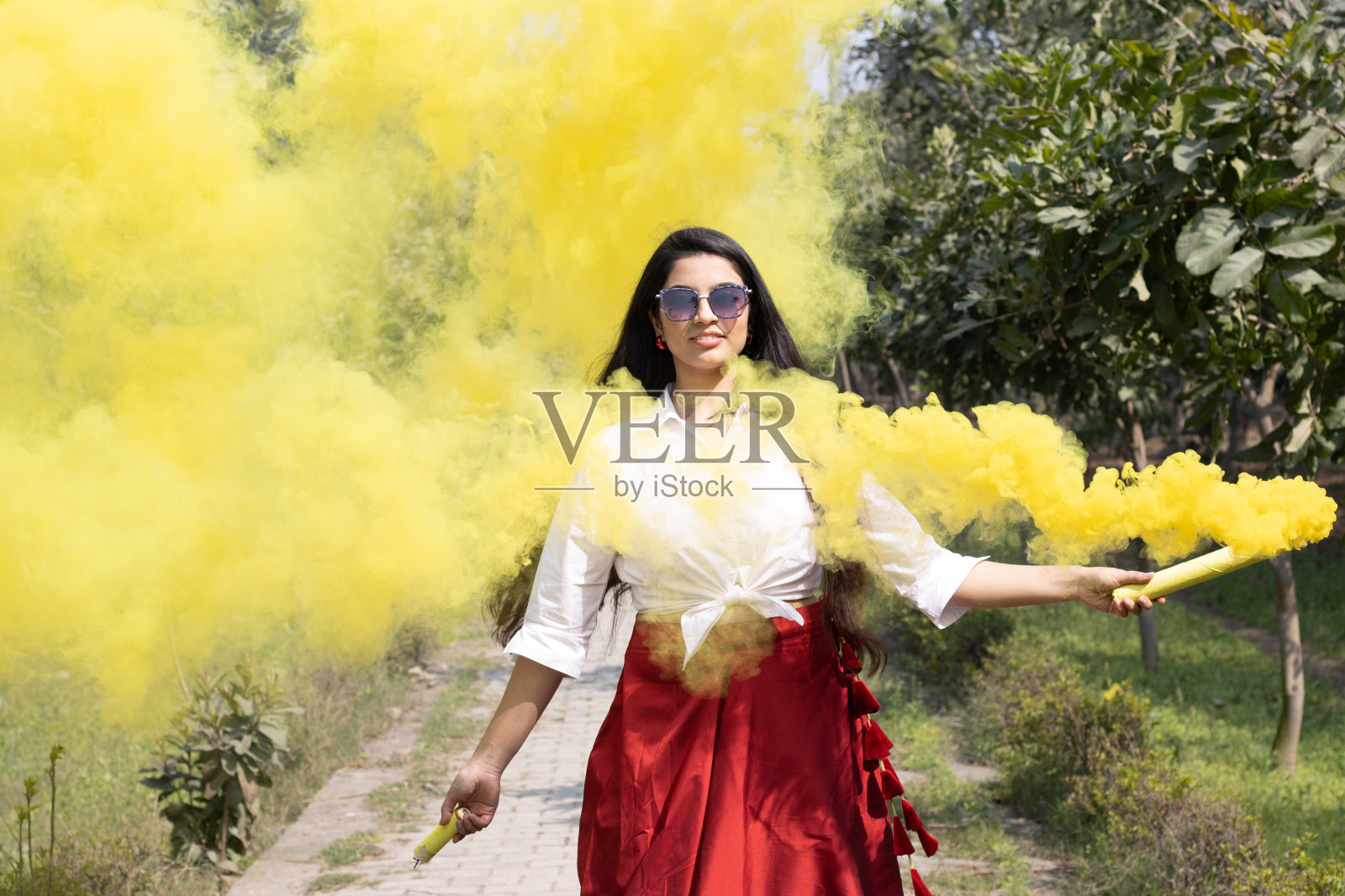 微笑的美丽的年轻女孩女人爆裂的烟雾弹颜色烟雾手榴弹云干燥的颜色胡里节粉末颜色gulal啤酒庆祝节日的颜色胡里节在公园春假照片摄影图片