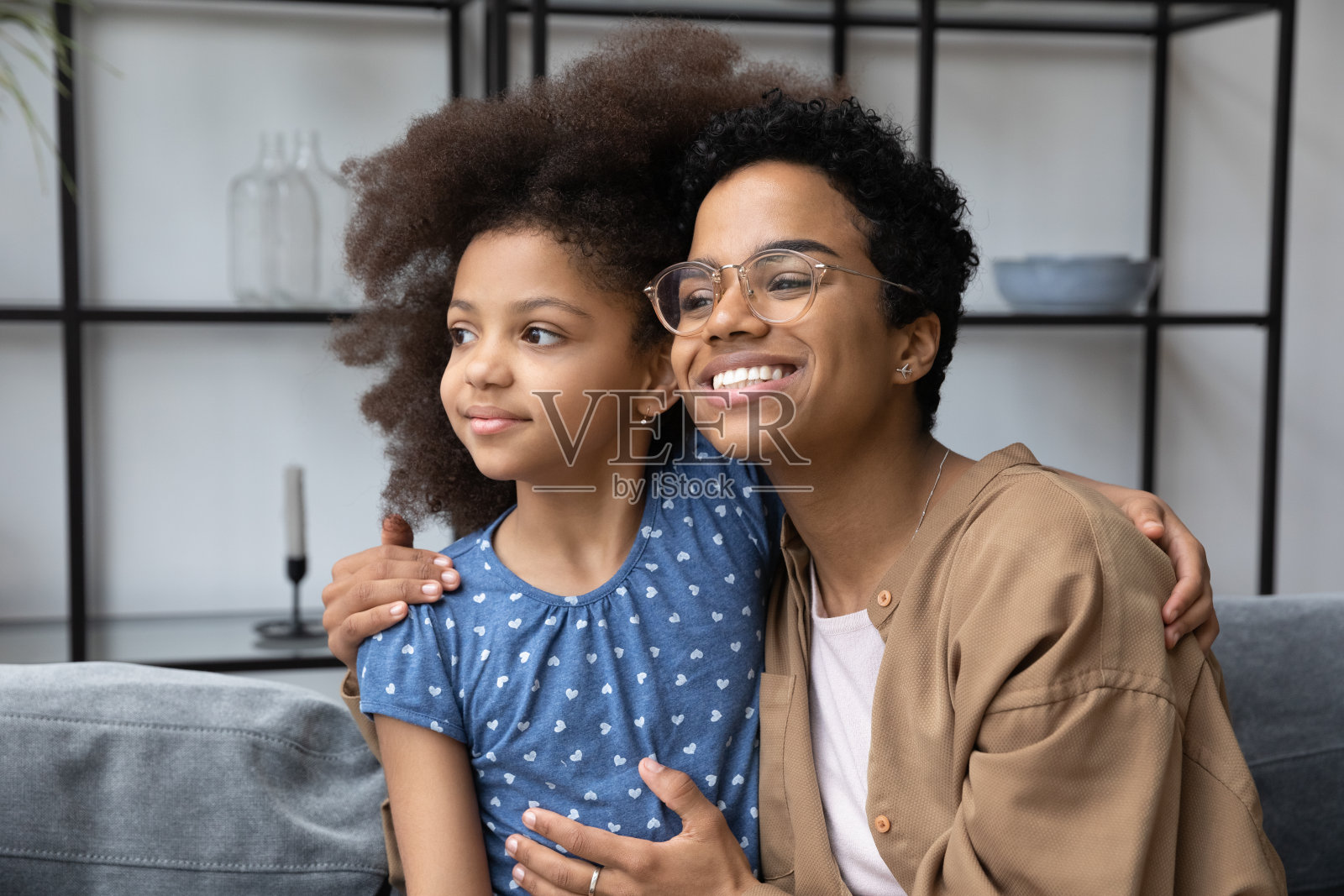 可爱的非洲裔美国年轻妈妈坐在沙发上照片摄影图片