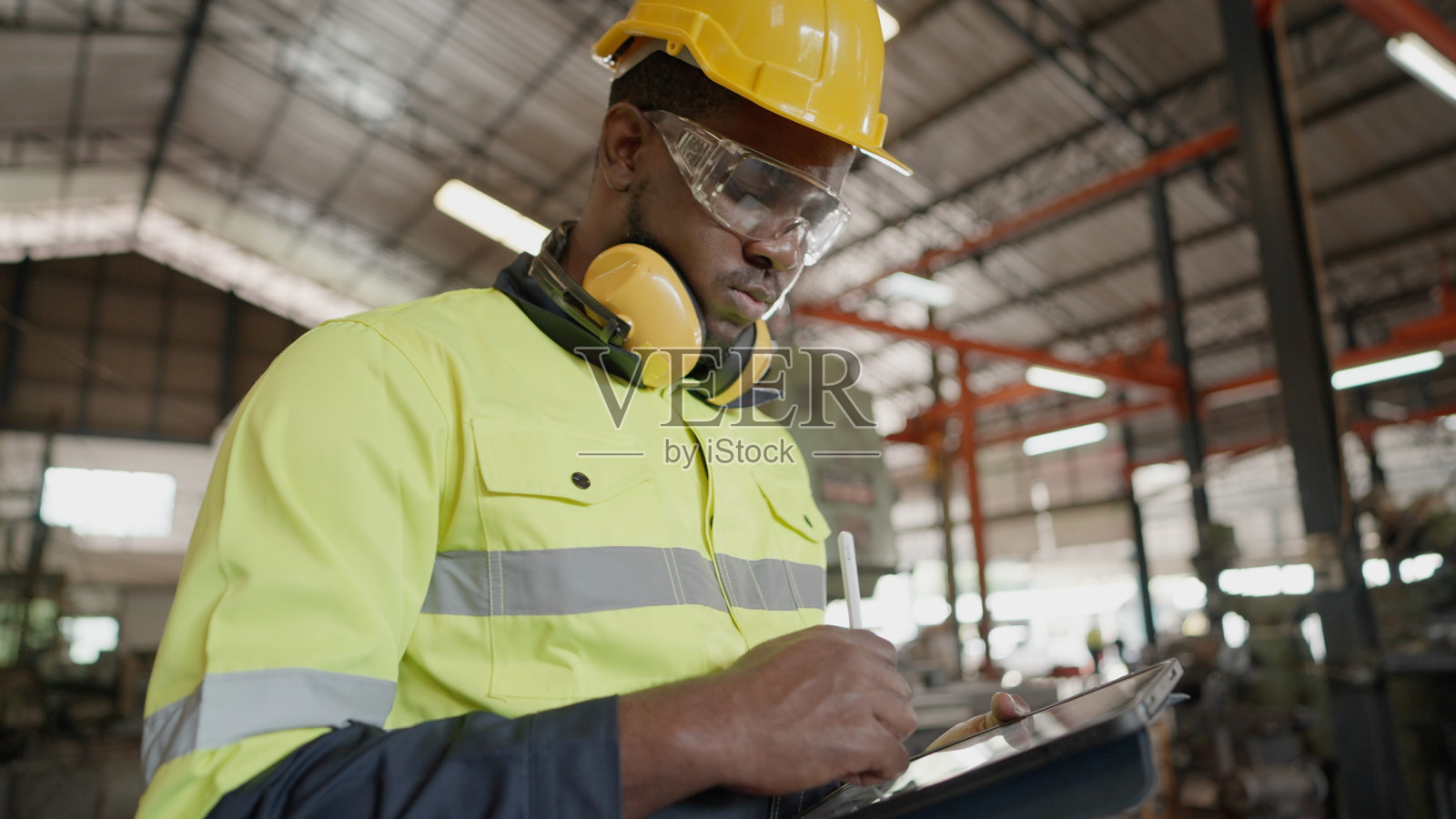 配合工业工程师或技术员领导,穿戴个人防护装备,站在制造工厂生产线上使用片剂检查原材料和库存。照片摄影图片