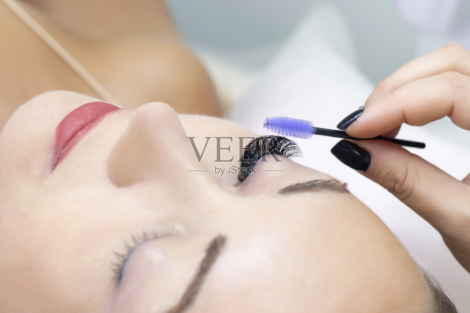 睫毛扩展过程。美容院的长睫毛美女。睫毛关闭。画笔的手照片摄影图片
