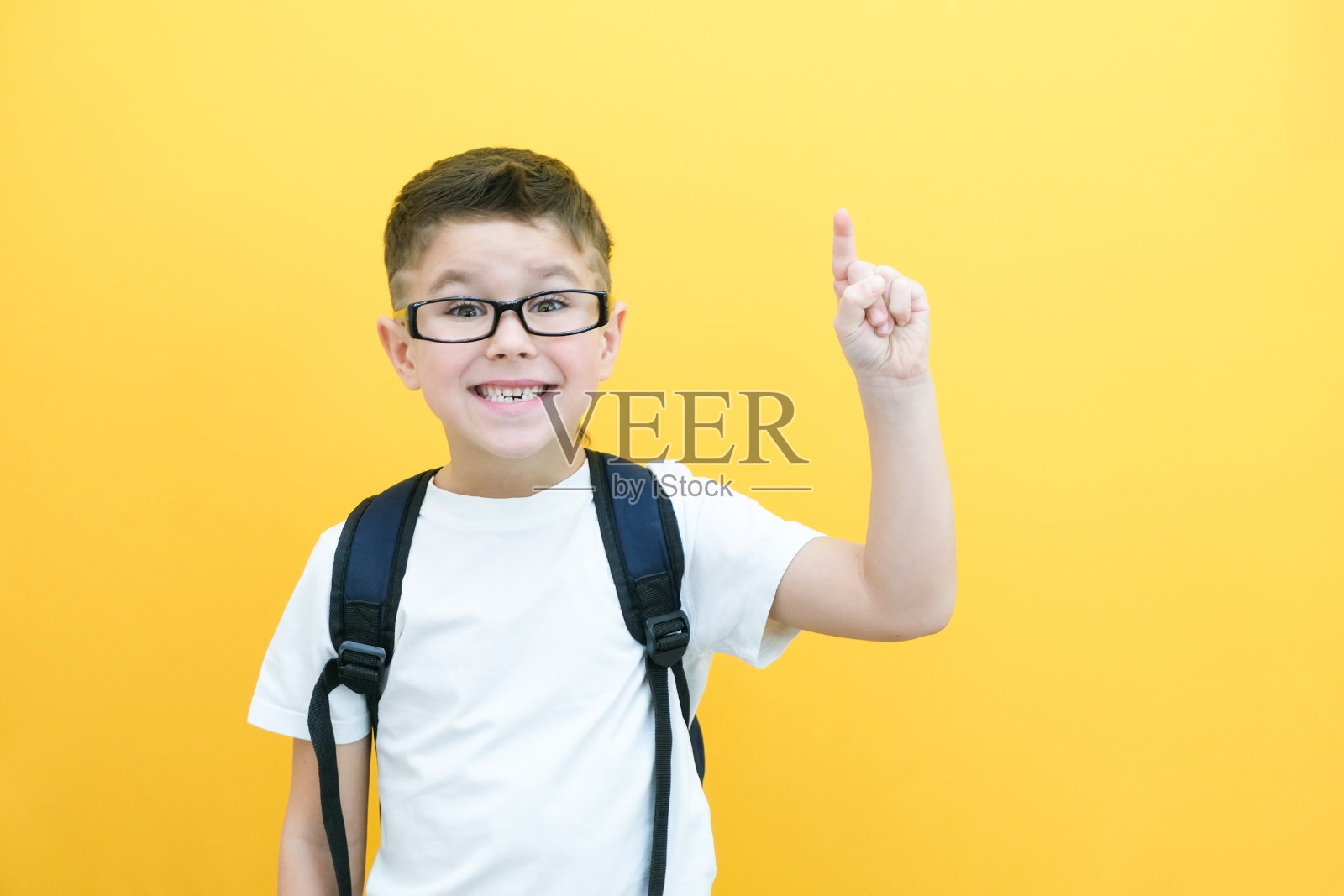 尤里卡,戴眼镜的英俊小男孩很惊讶,灵感来了,我有个主意,竖起食指,复印空间,孤立在黄色背景上。照片摄影图片