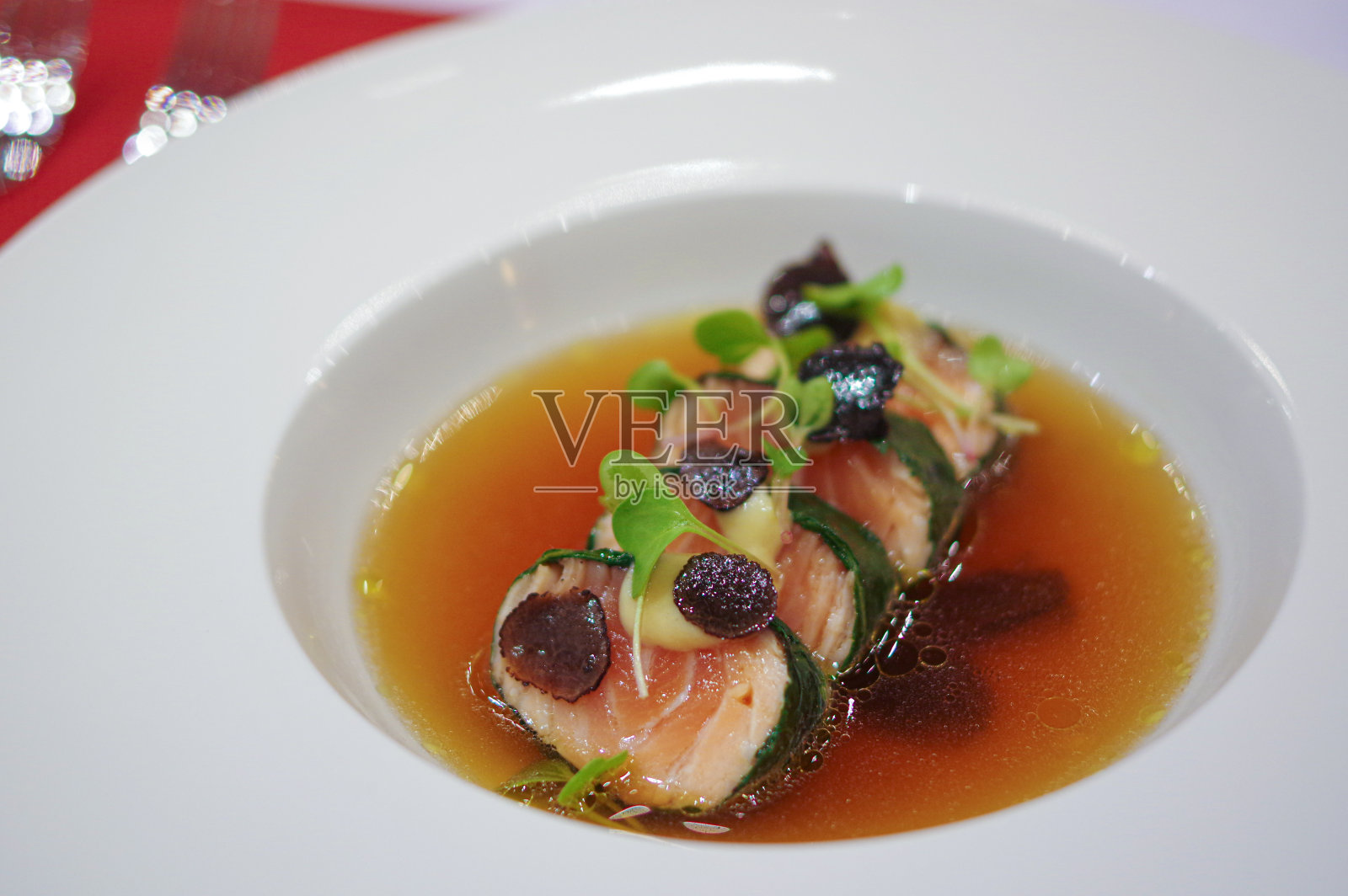 紫菜包裹的鲑鱼卷与黑松露切片和芽菜在汤碗盘照片摄影图片