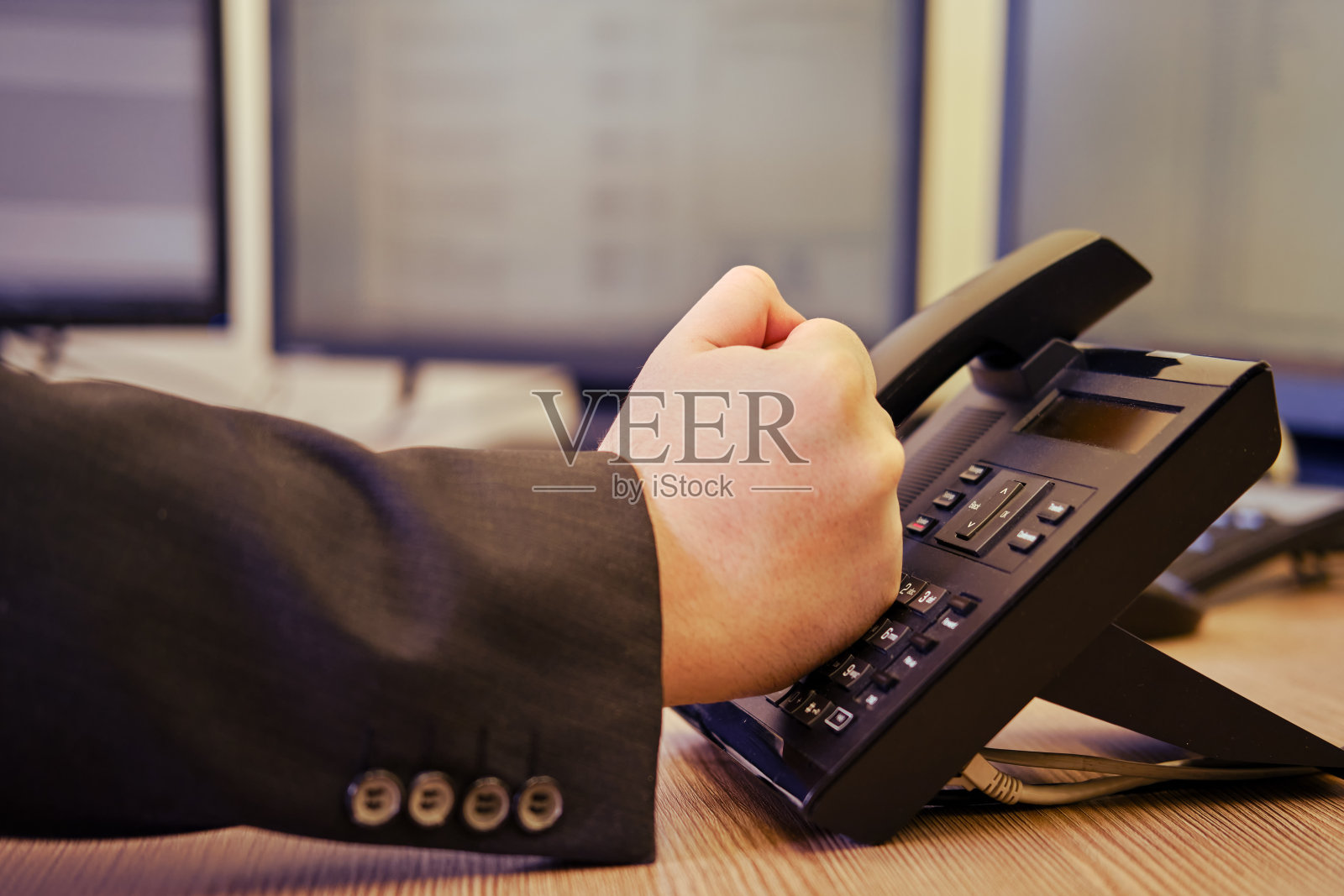 穿着西装的愤怒的商人在办公室用座机打电话,男人拳头特写照片摄影图片