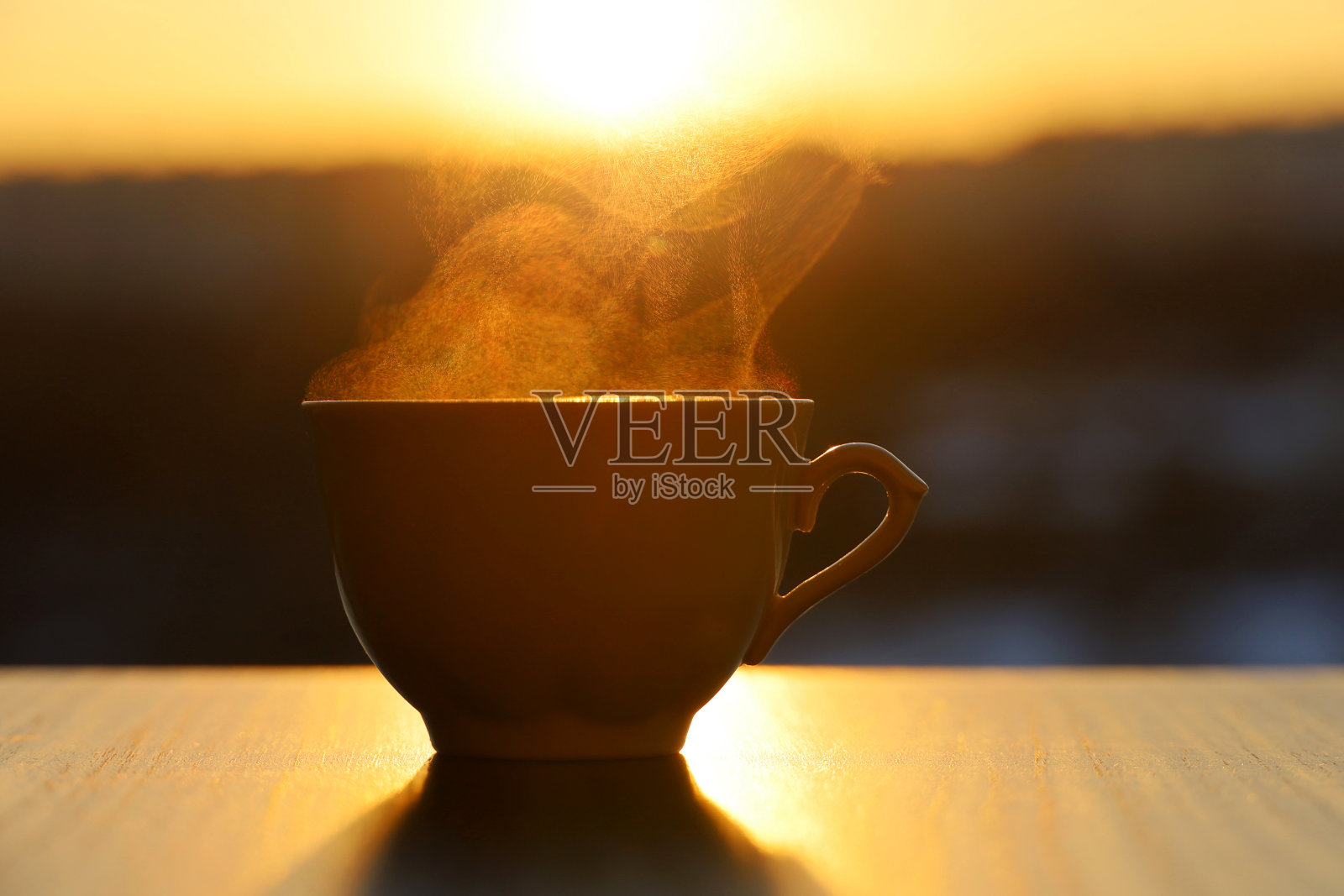 热咖啡或茶杯与烟在日落的背景照片摄影图片