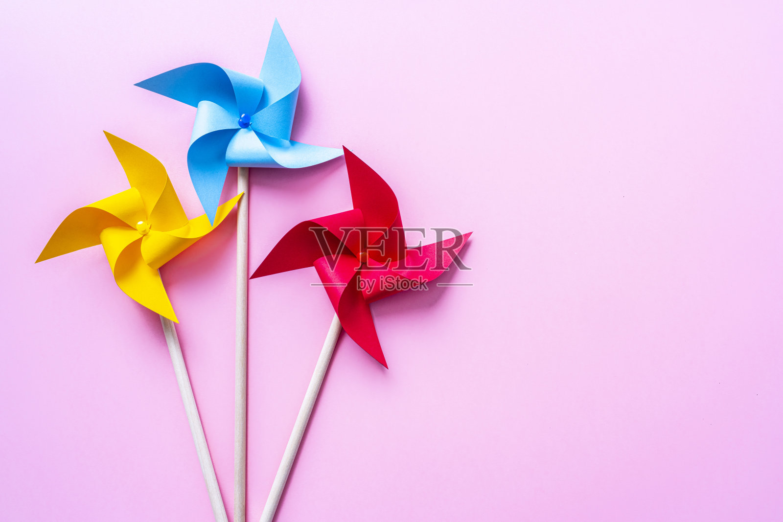 粉红色背景上的彩色风车。本空间照片摄影图片