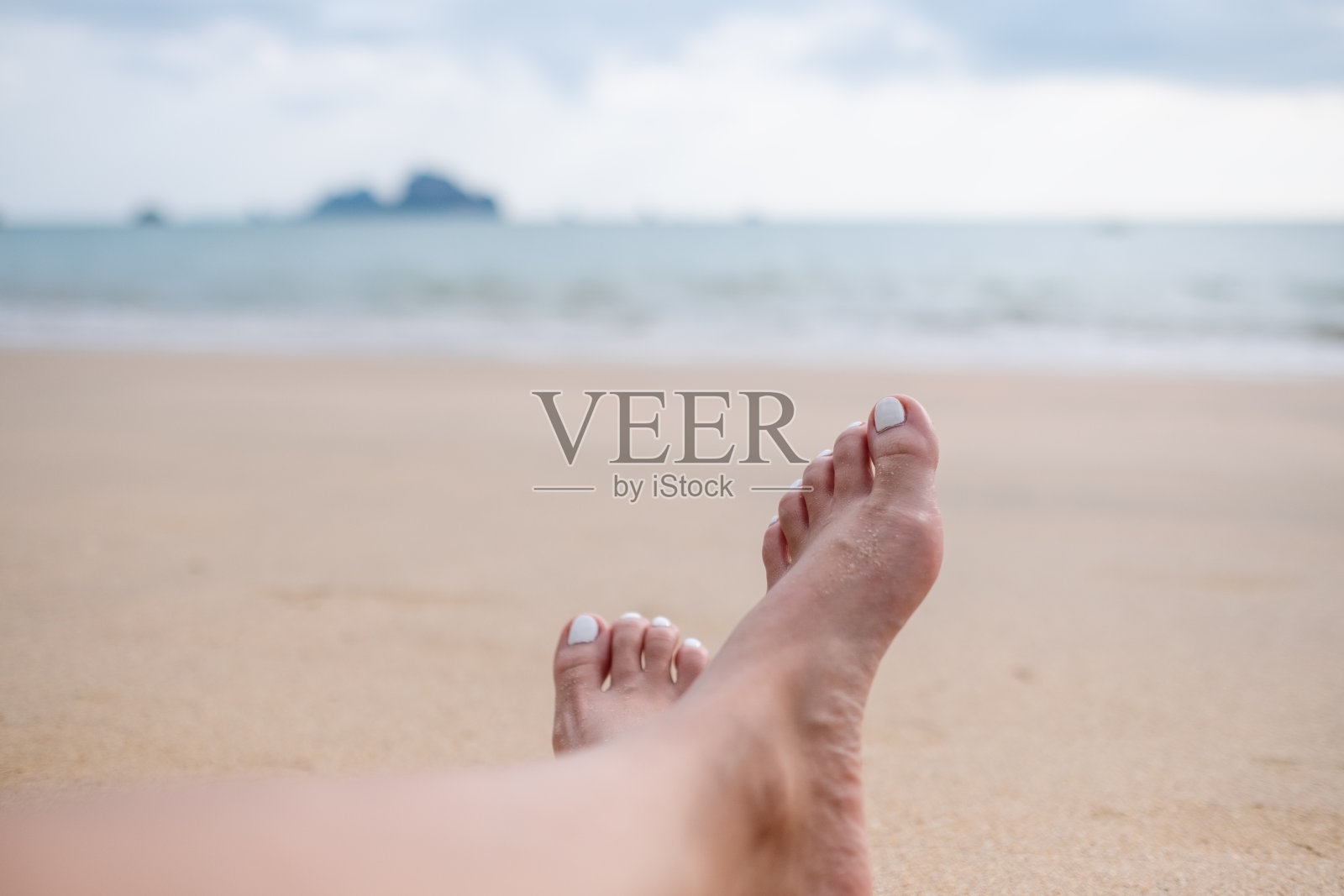 特写图像的女性的腿和脚,而坐在海边蓝色的天空背景照片摄影图片