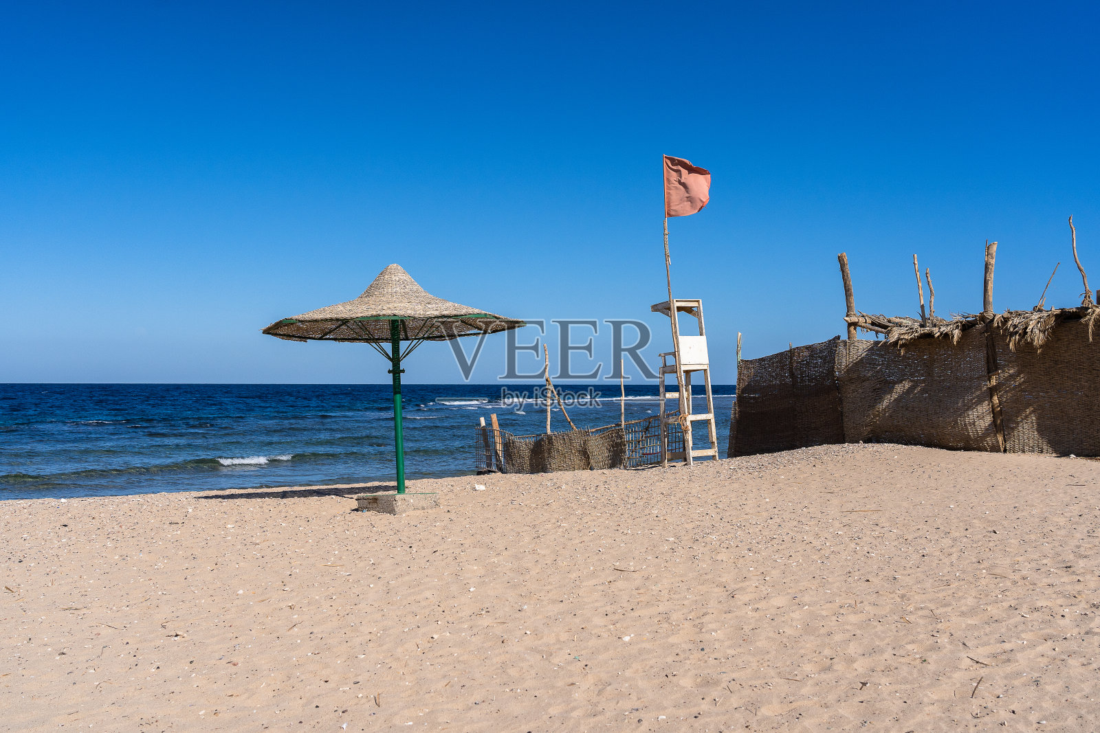 沙滩上的芦苇伞和救生员椅状况不佳照片摄影图片