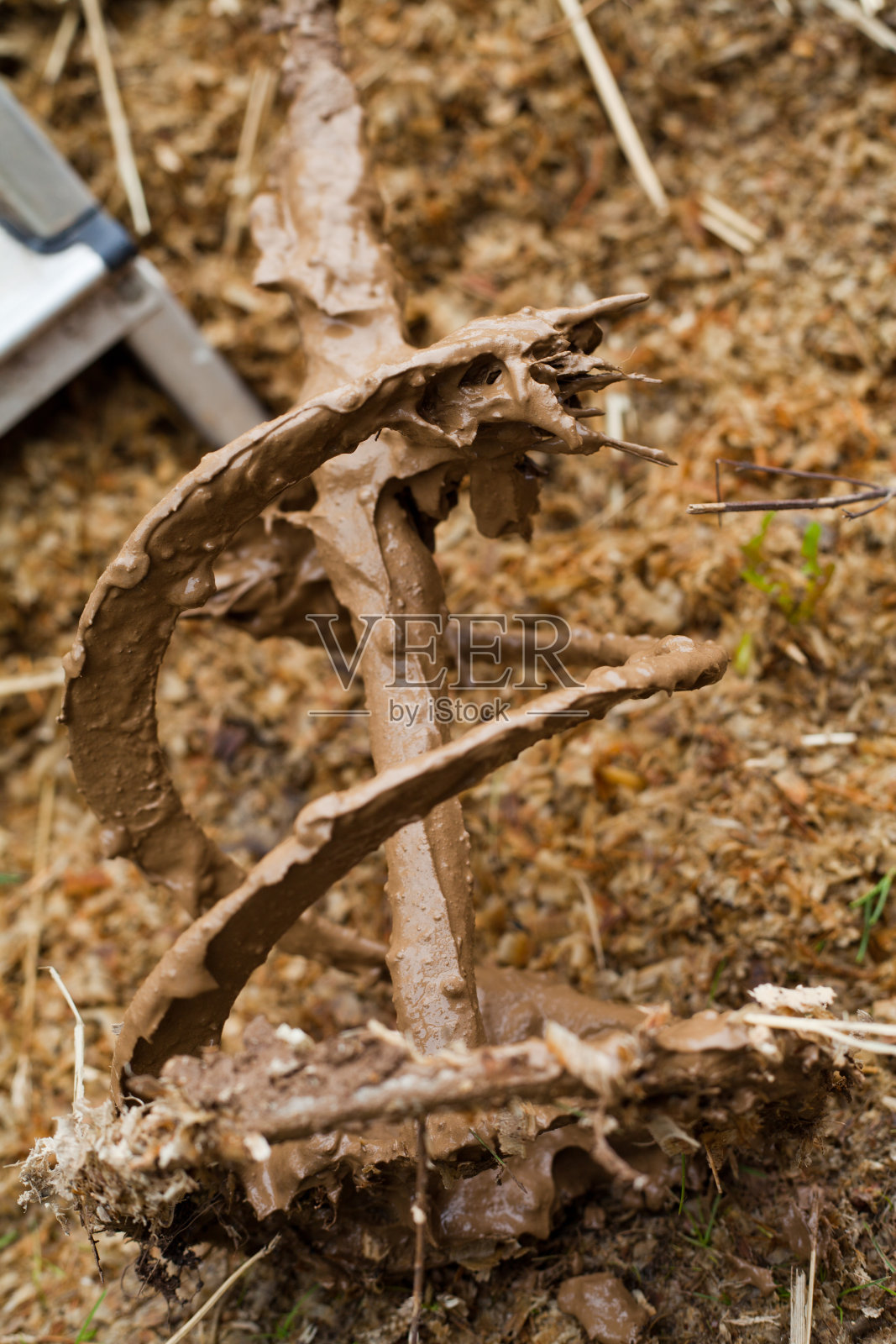 用稻草和粘土建造房屋-在建筑工地用混凝土搅拌机搅拌红粘土。传统建筑的古老技术。照片摄影图片