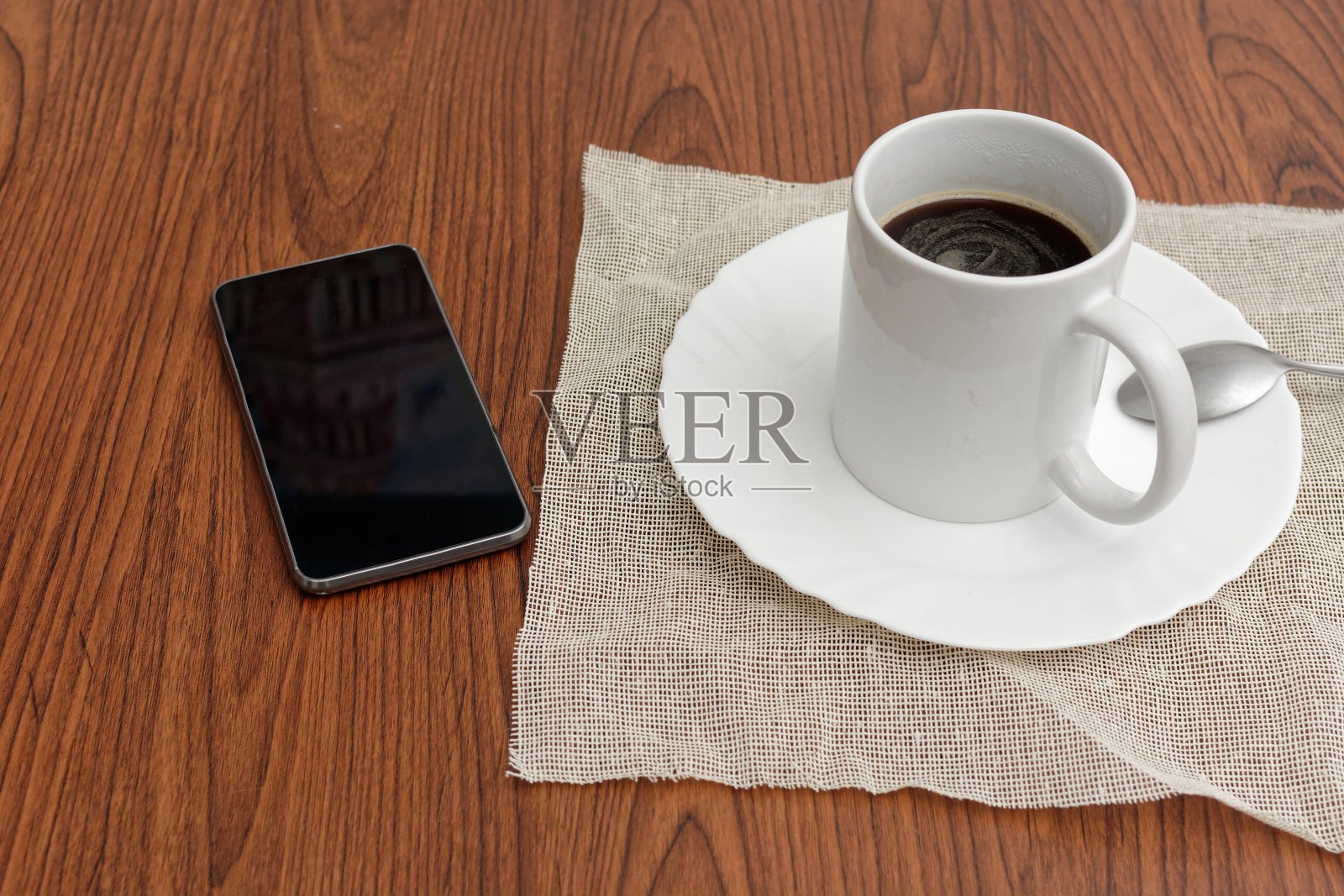 木桌上放着咖啡和手机。照片摄影图片
