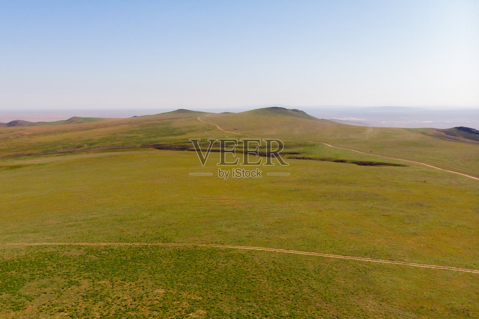 山脚下山谷里一望无际的大草原。俯瞰青山。山上,绿树成荫照片摄影图片