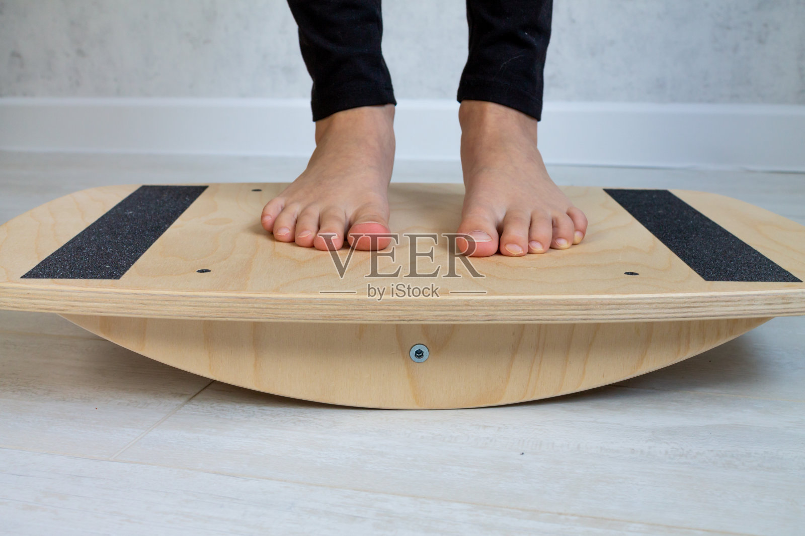 孩子从脚外翻开始用平衡器进行练习。孩子的腿被拉近了。儿童物理治疗课程照片摄影图片