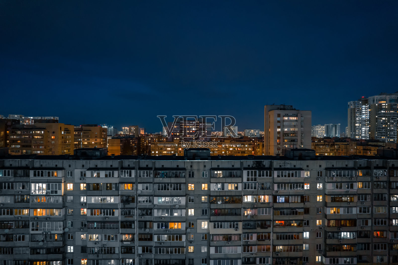 夜晚旧公寓大楼的窗户。照片摄影图片