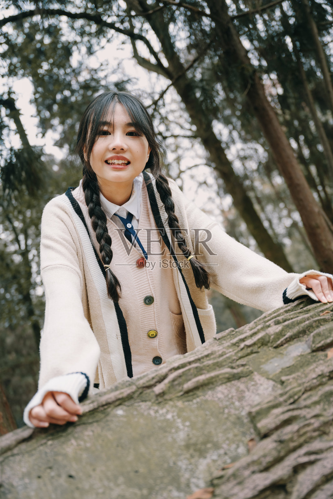 一个美丽的亚洲女孩坐在石凳上照片摄影图片