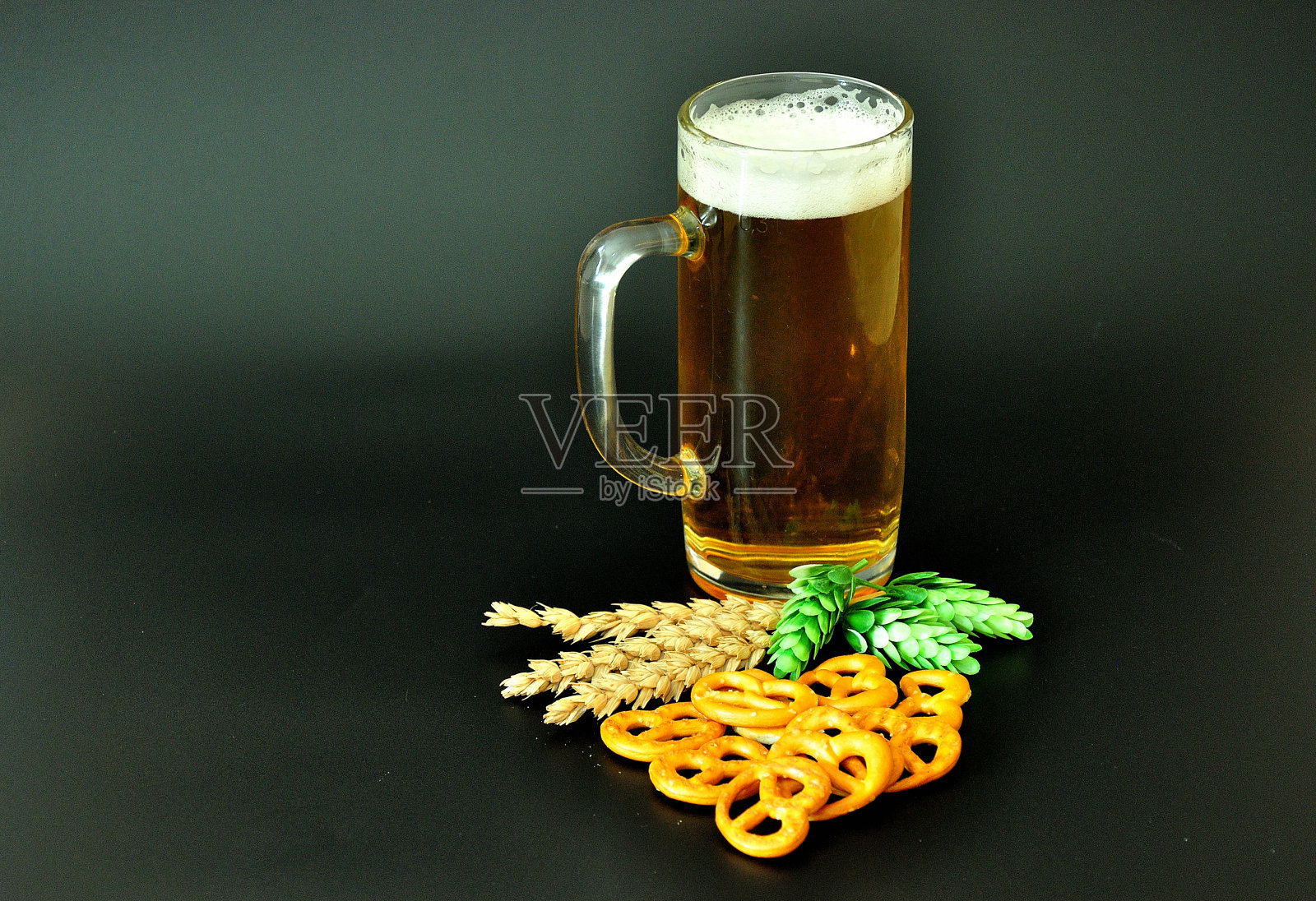 一杯淡啤酒,黑色背景上的景象,啤酒花和谷物。照片摄影图片